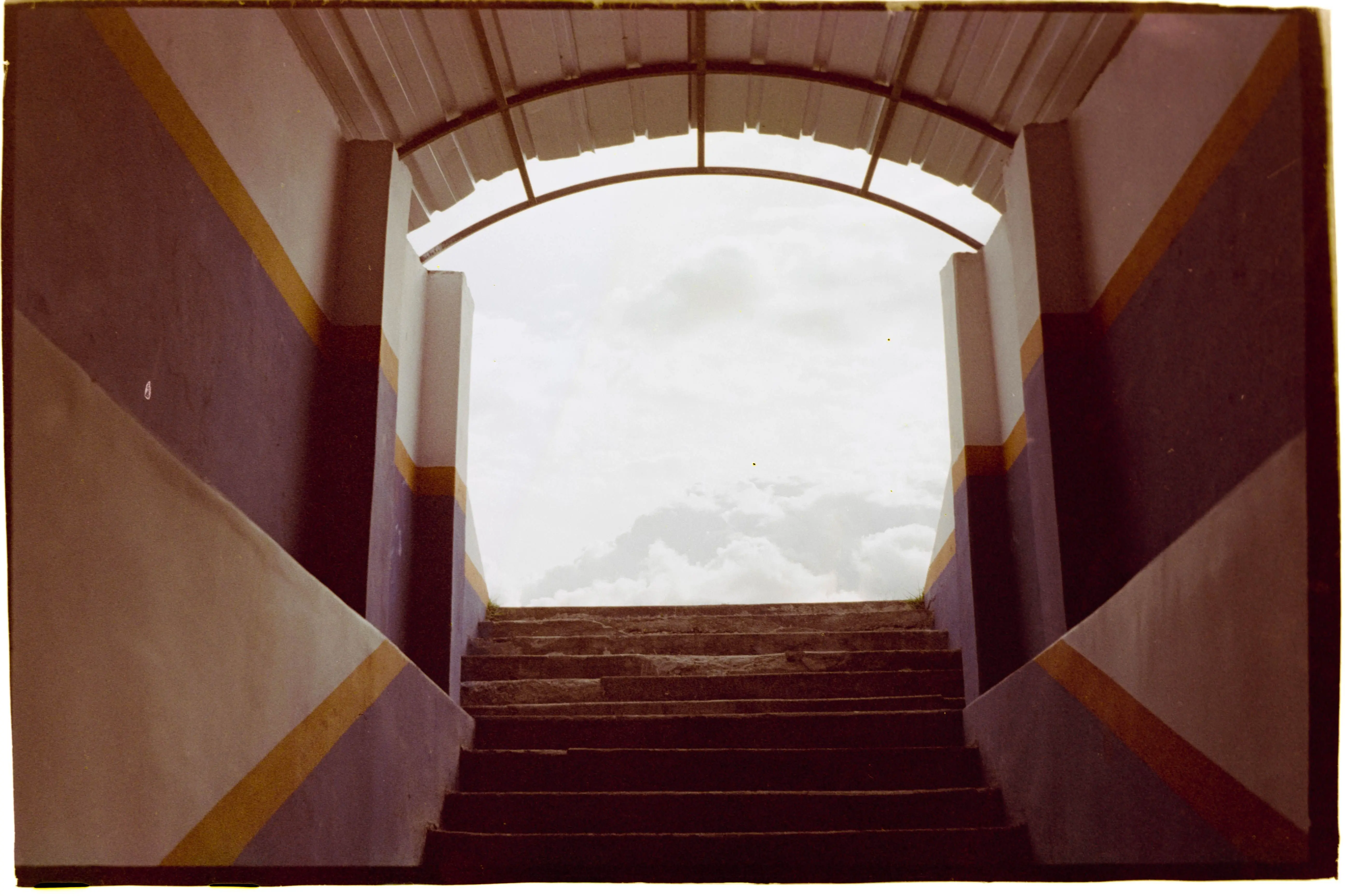 outdoor path lights Architectural stairs leading to a bright, cloudy sky, framed by colorful walls.