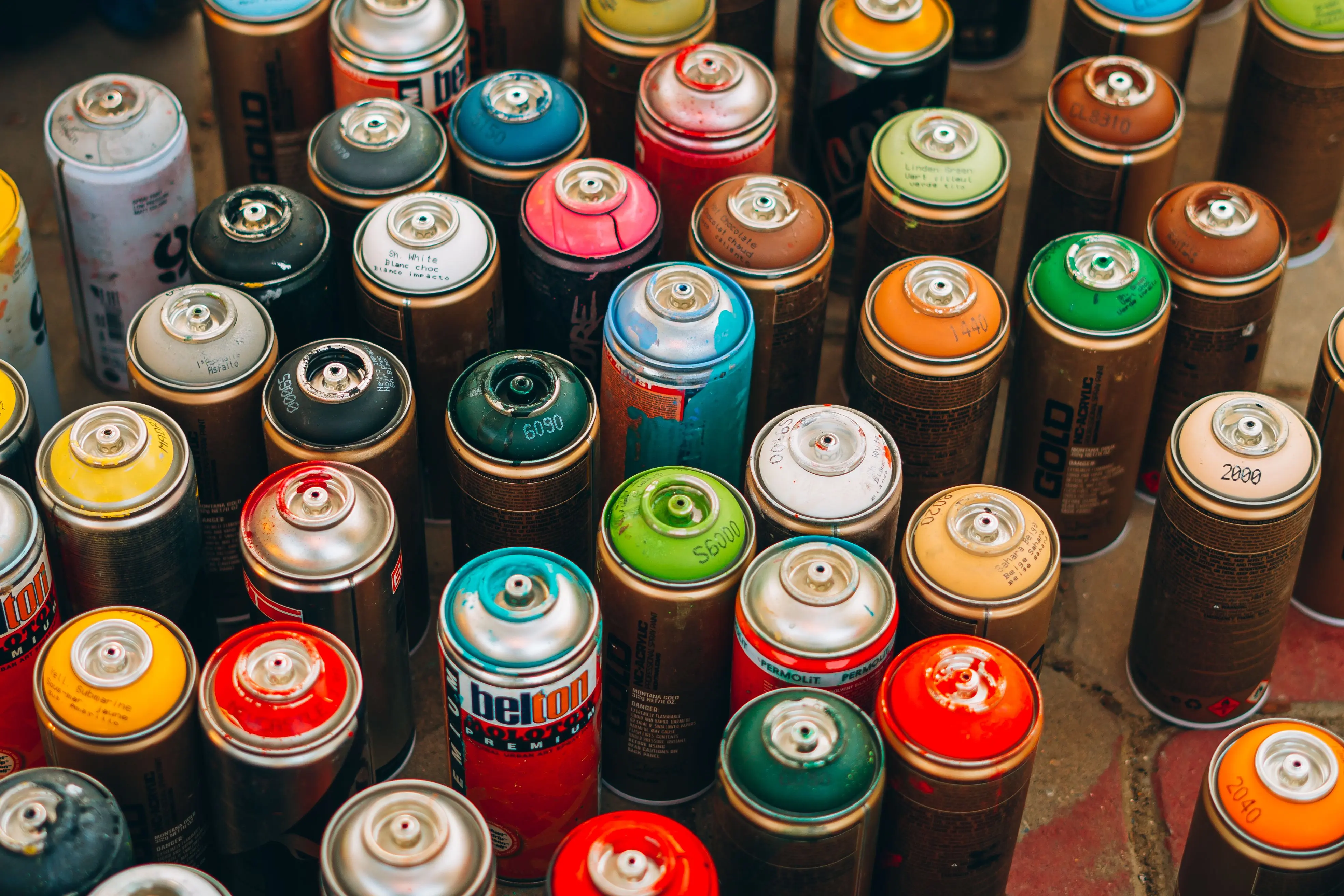 patio paint Collection of colorful spray paint cans on a concrete surface, ready for creative urban art projects.