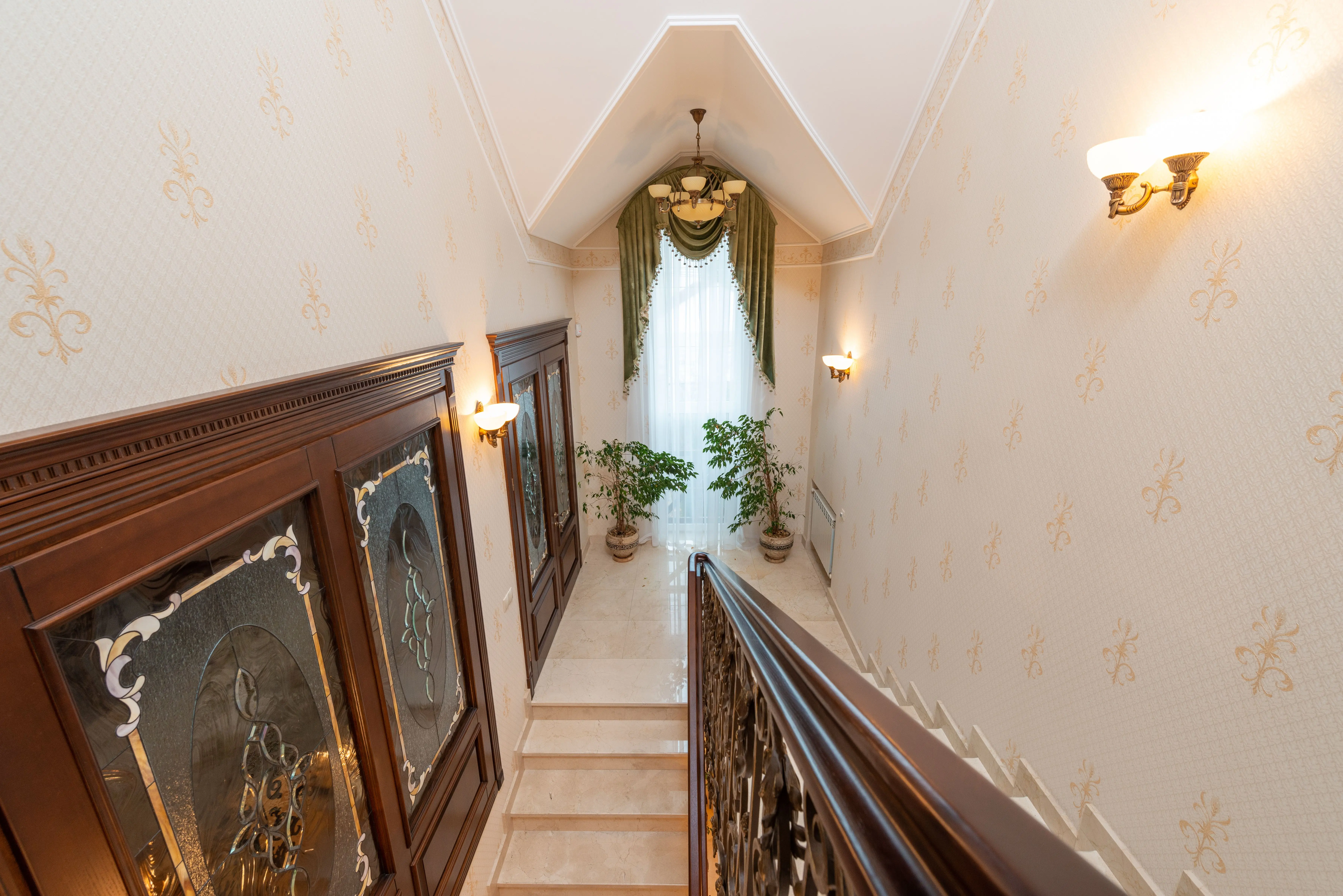 outdoor sconce lights Stylish interior staircase with vintage chandelier and potted plants in elegant design.