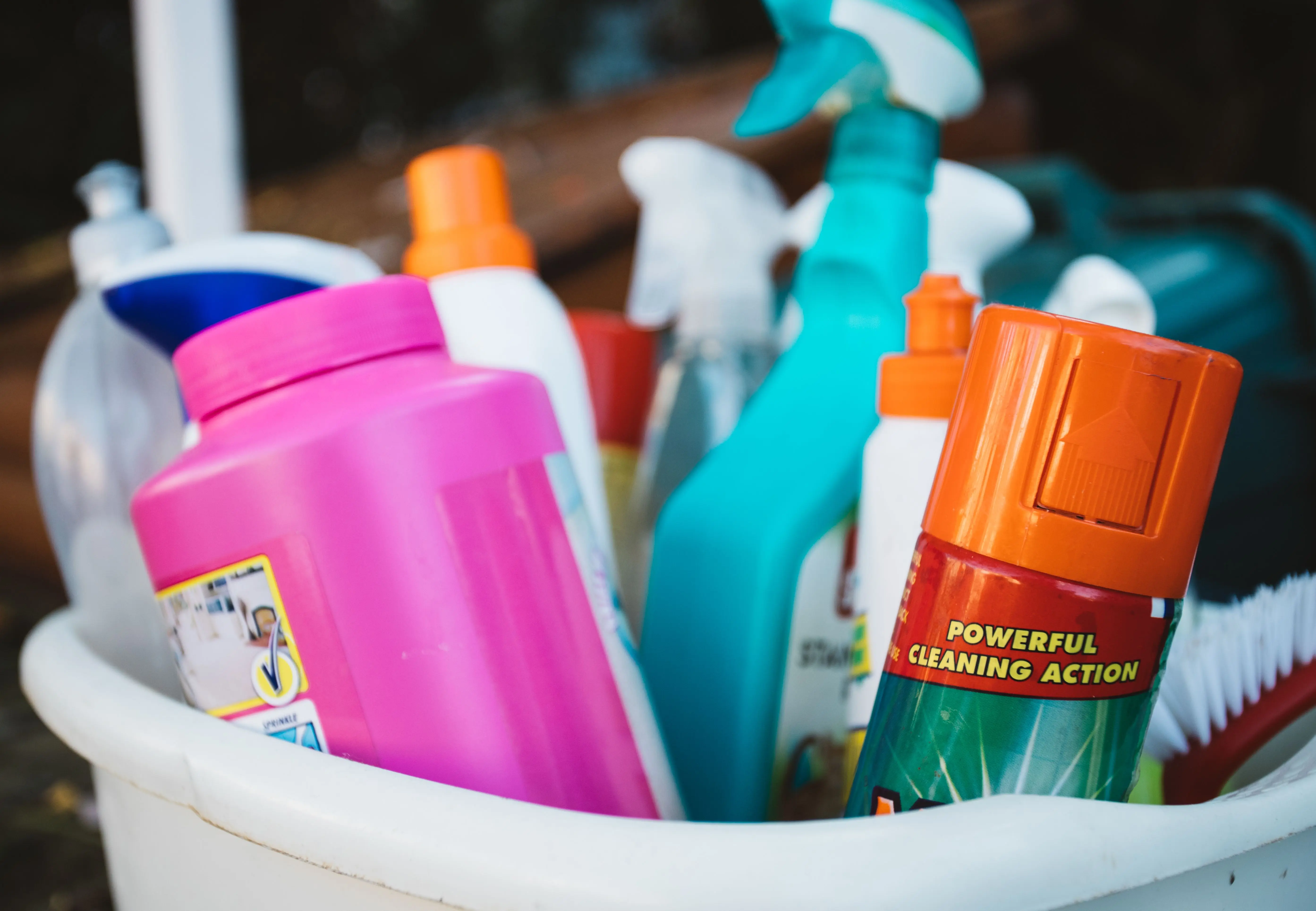 how to get dried blood out of clothes Close-up of assorted cleaning supplies in a bucket outdoors, showcasing various detergents and sprays.