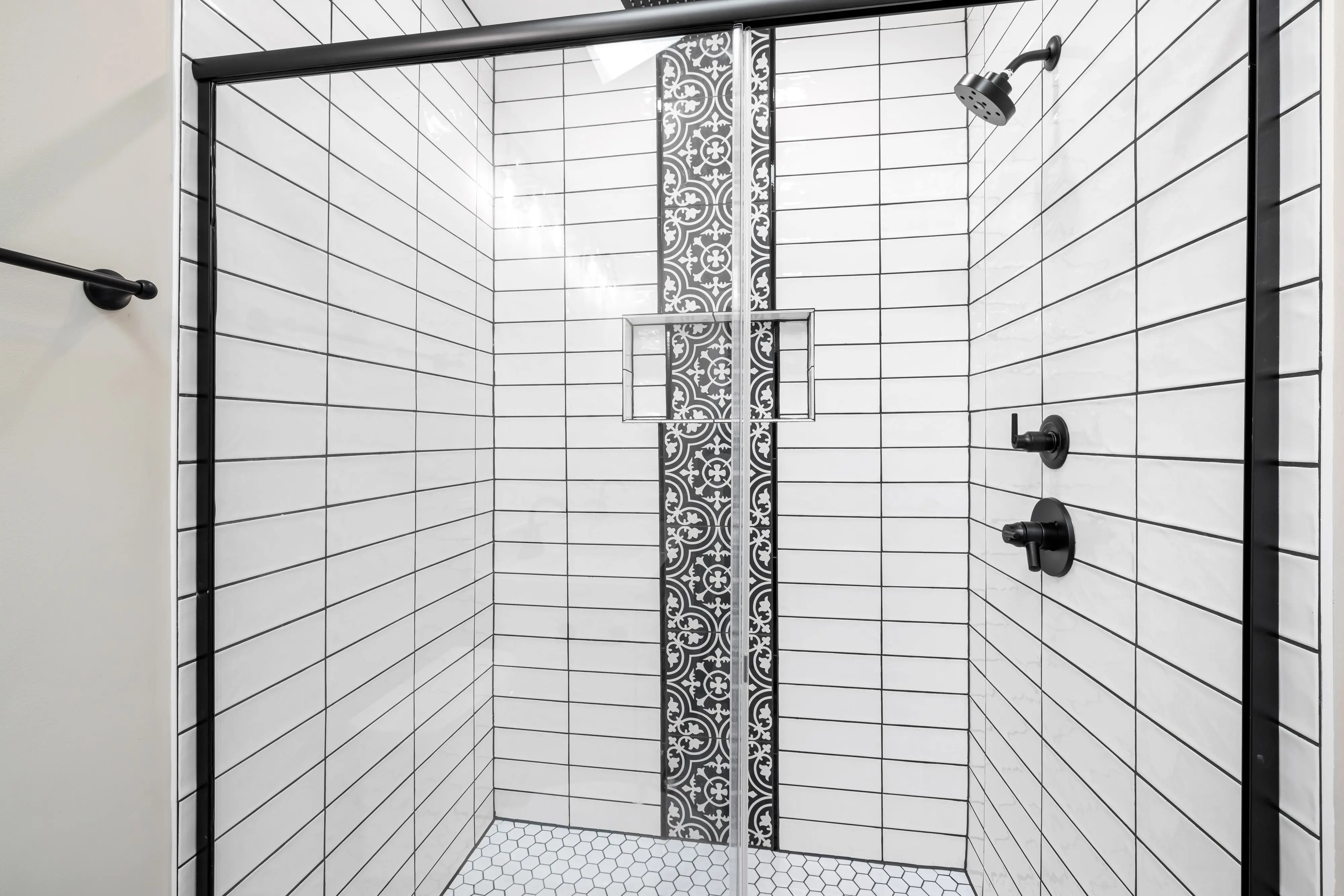 modern kitchen backsplash Stylish shower with white subway tiles and a striking black patterned accent wall for a modern touch.