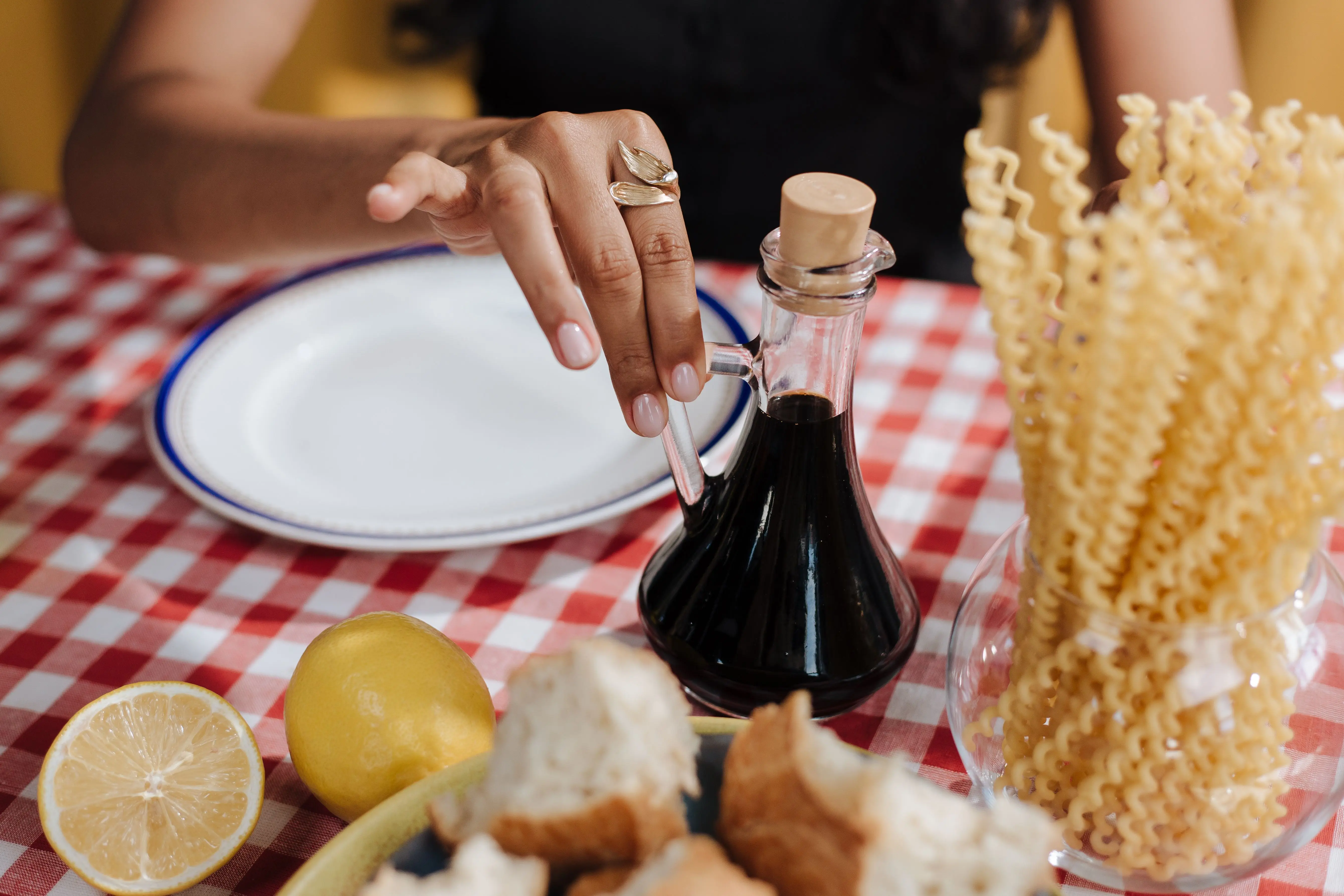 what scent do flies hate A close-up of a hand reaching for vinegar at an Italian-themed table.