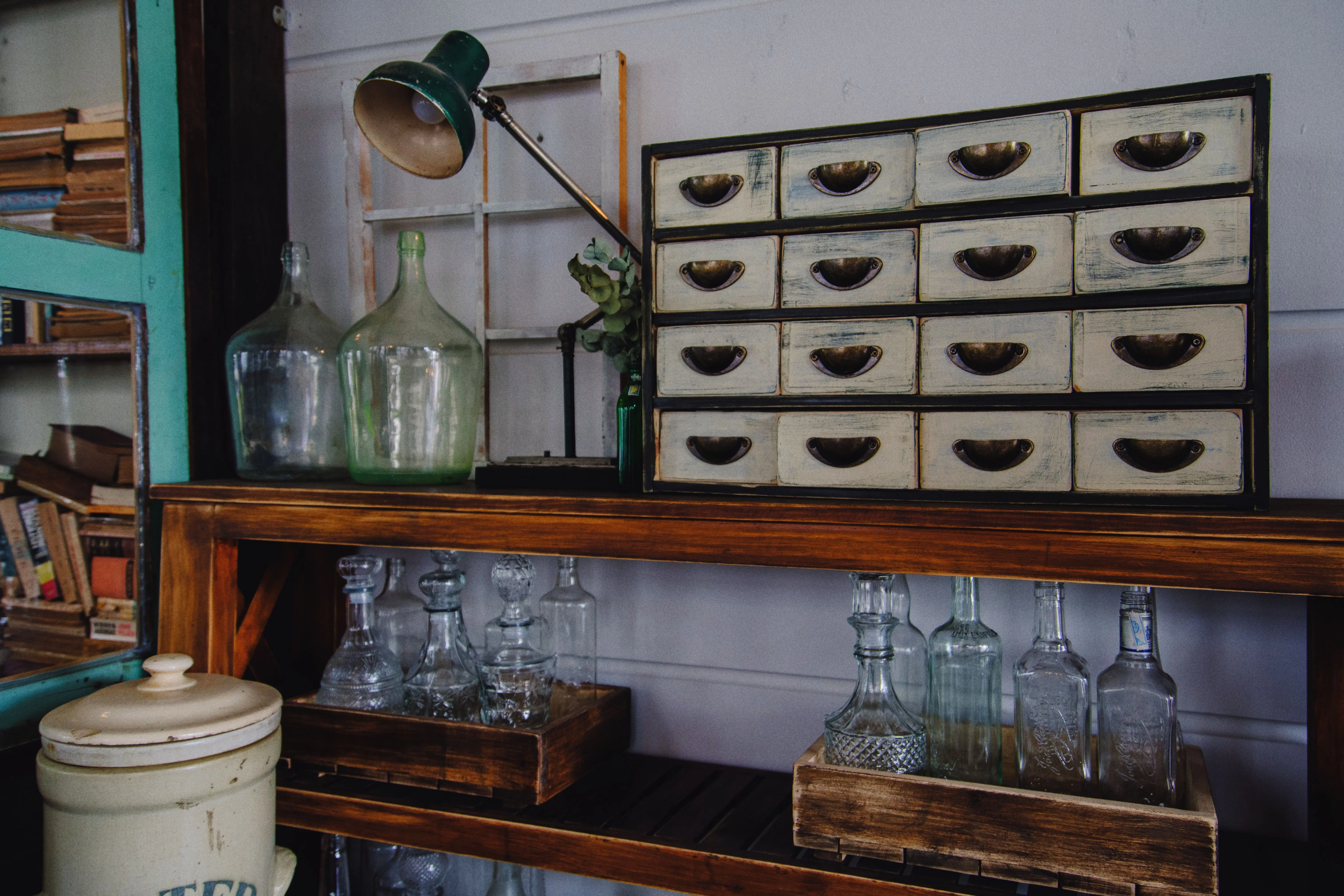 wooden drawer A rustic indoor scene featuring a vintage cabinet and glass bottles on a wooden shelf.