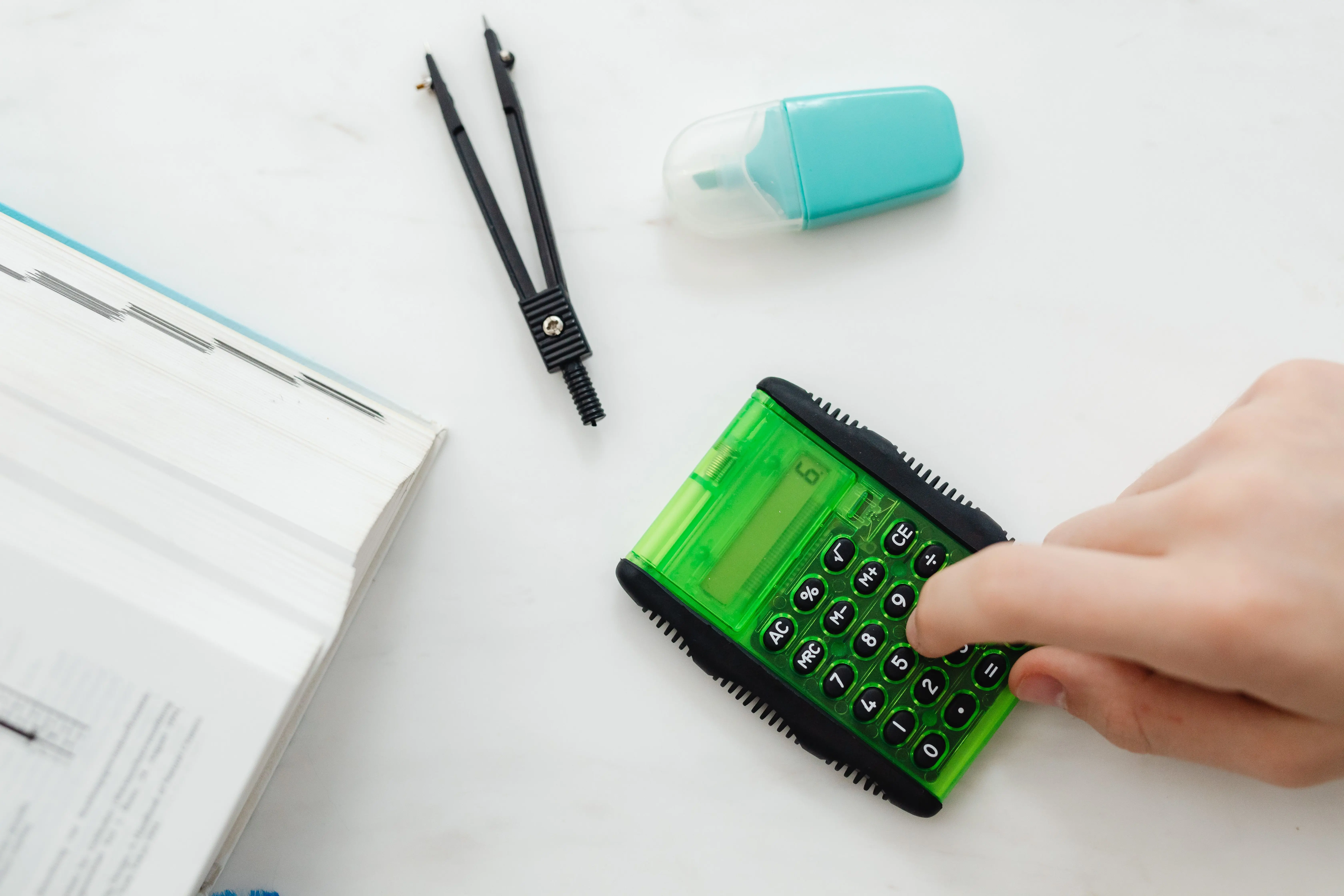 window replacement cost calculator Close-up of a hand using a green calculator with stationery for studies or business calculations.