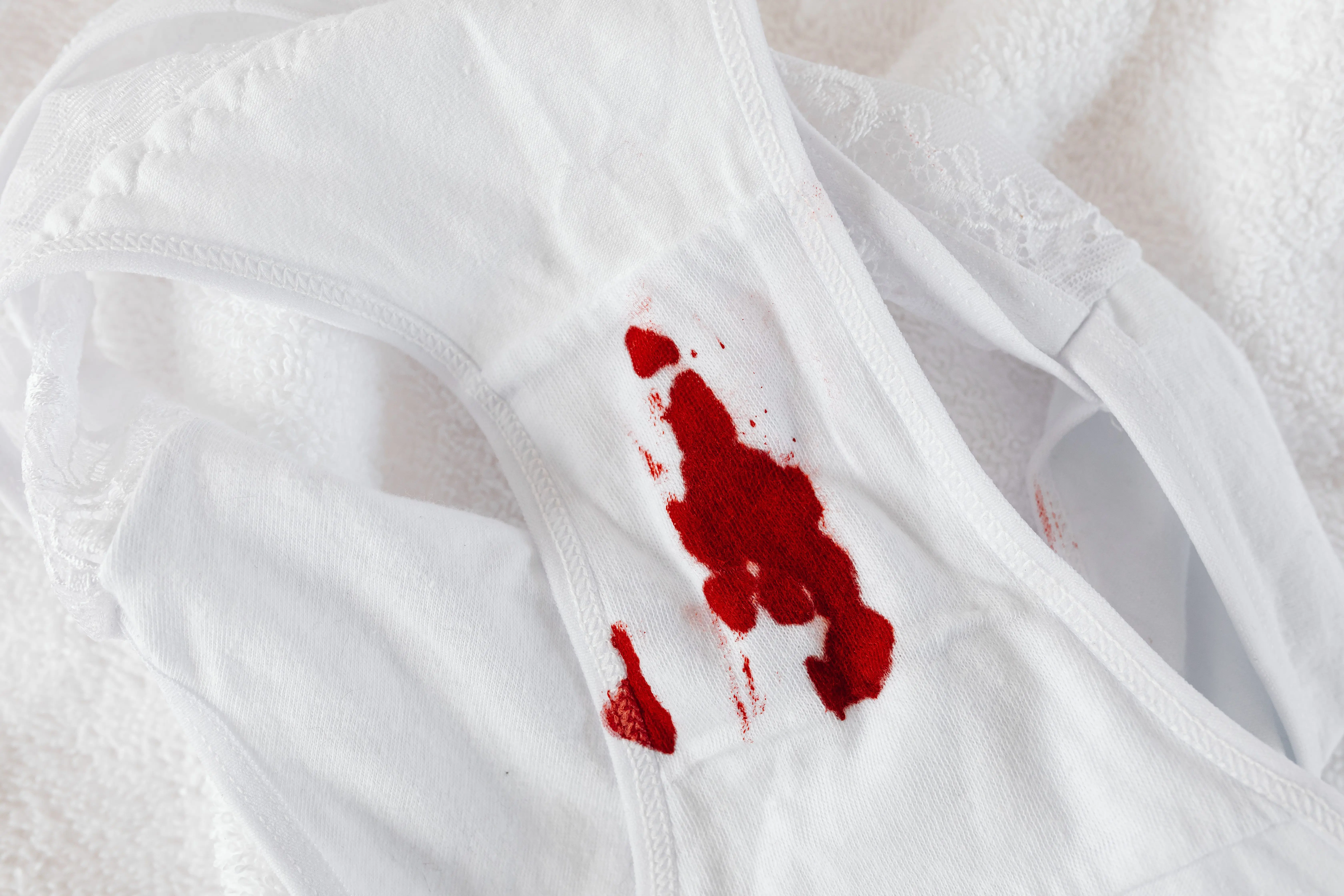how to get blood stains out of jeans Close-up of white panties with red menstrual blood stain on white background.