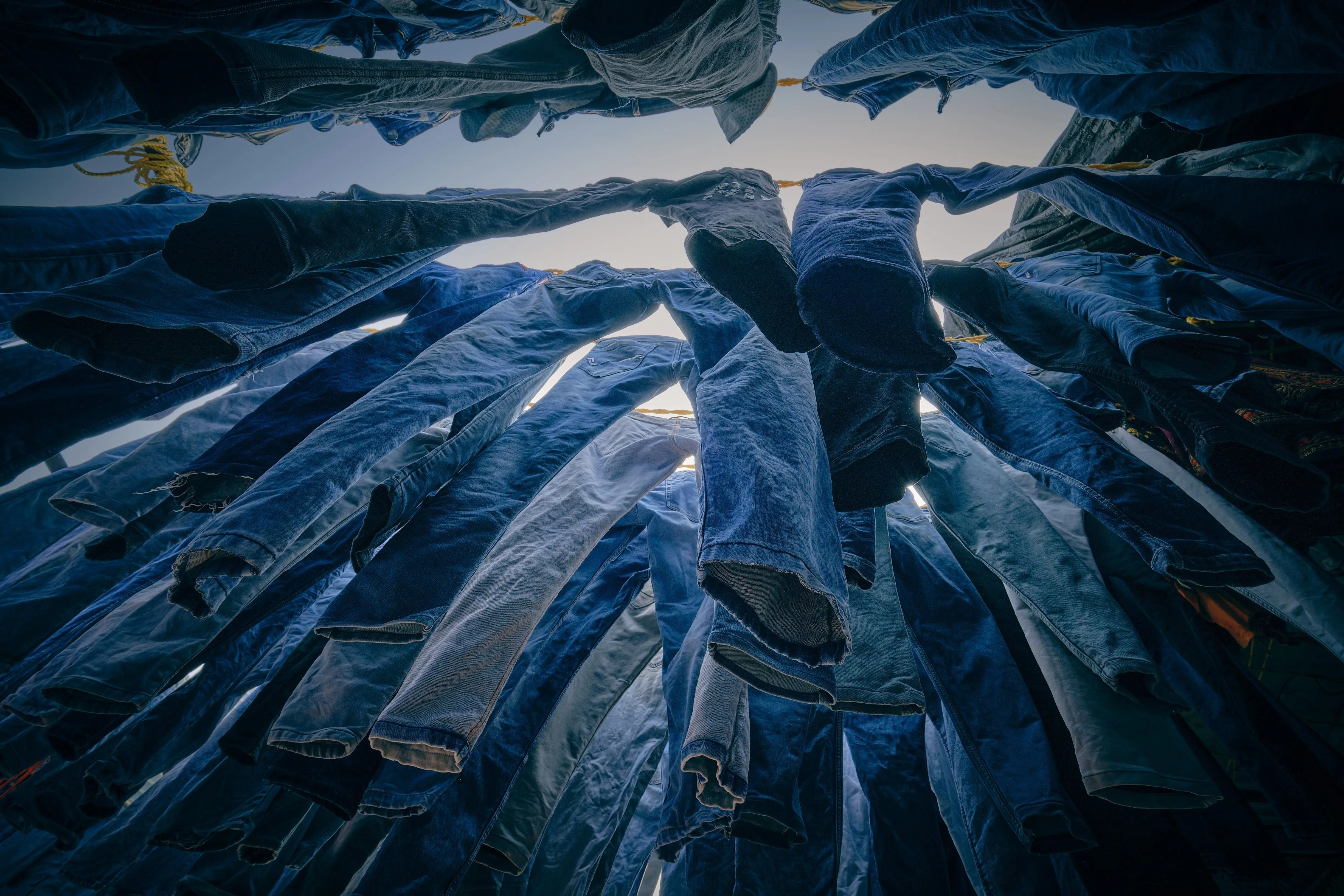 how to get blood stains out of jeans View of denim jeans hanging on a clothesline drying outdoors on a sunny day.