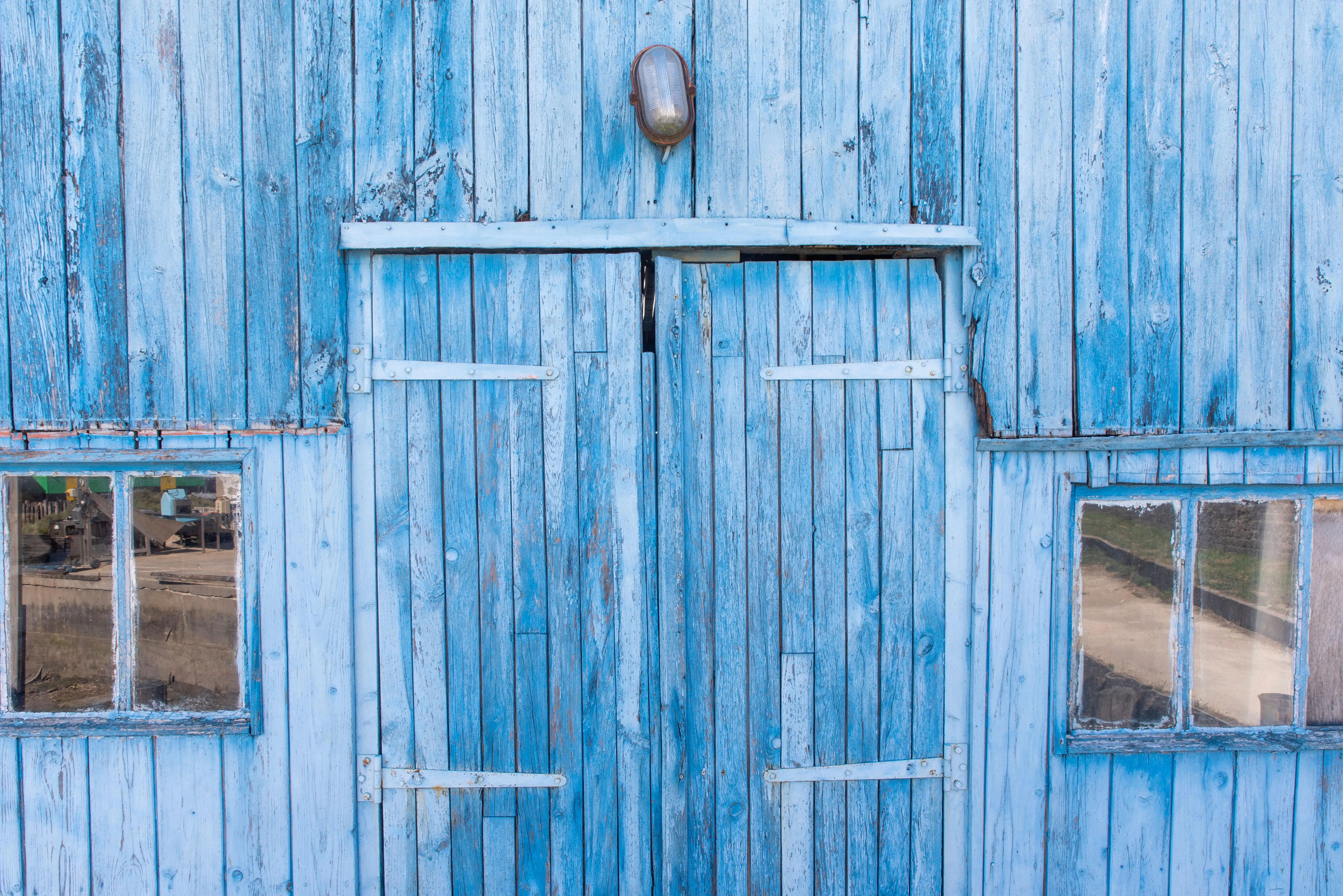 rustic wall art decor A rustic blue wooden barn door with glass windows, showcasing a weathered, vintage look.
