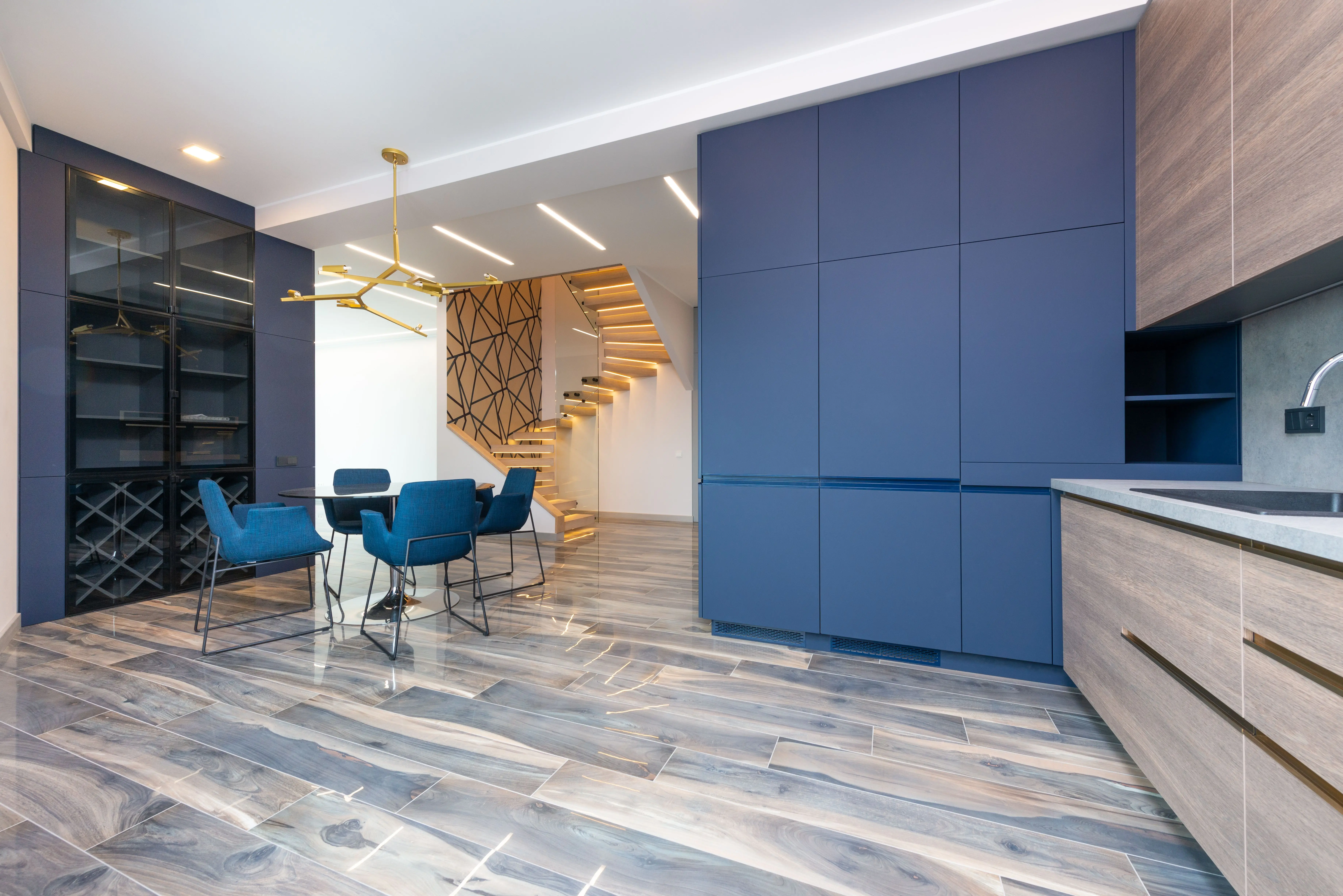 laminate cabinets Contemporary kitchen with cabinets and table with armchairs against staircase on floor in light house