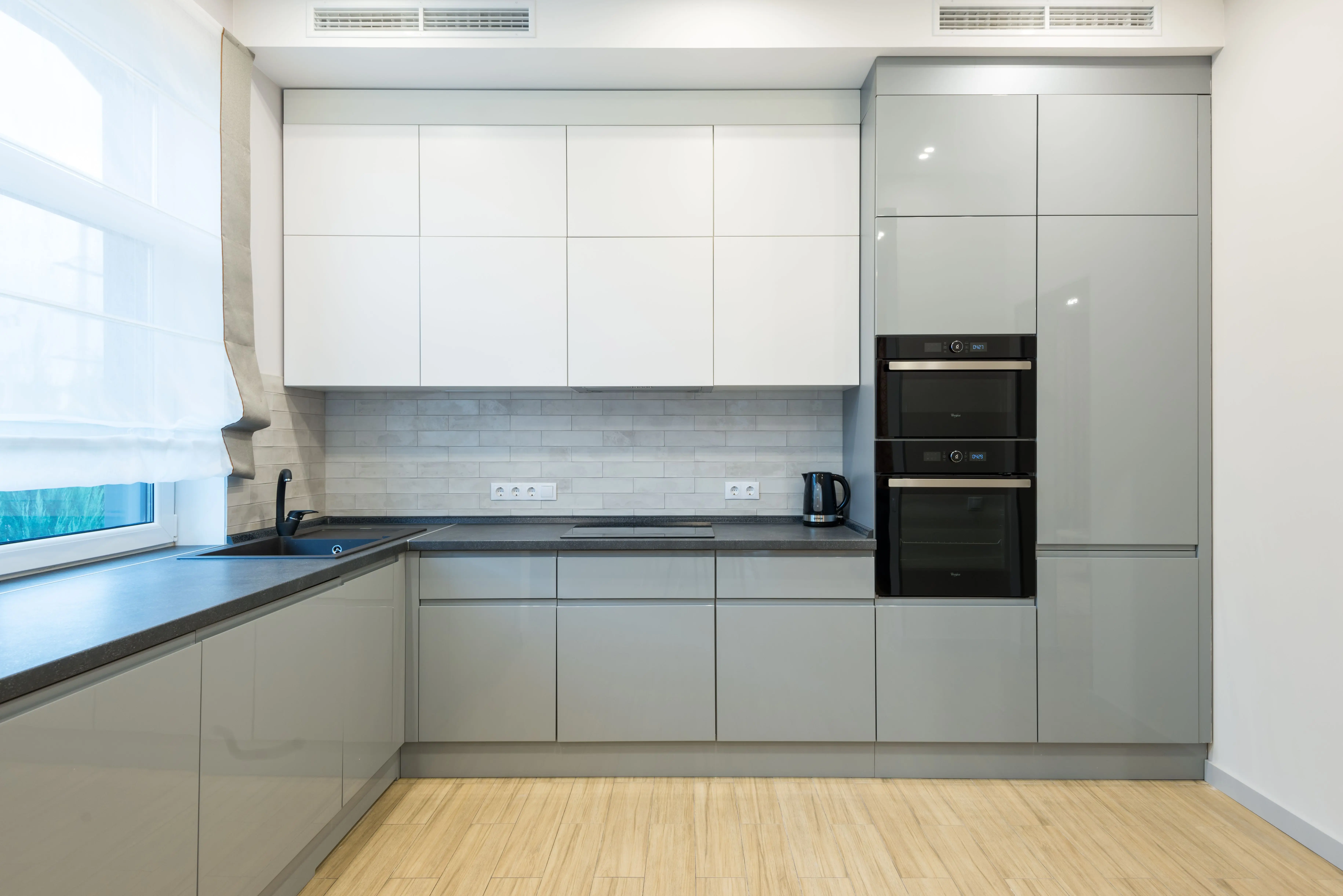 laminate cabinets Interior of contemporary kitchen with gray and white cabinets with sink and modern oven near electric cooker in spacious apartment