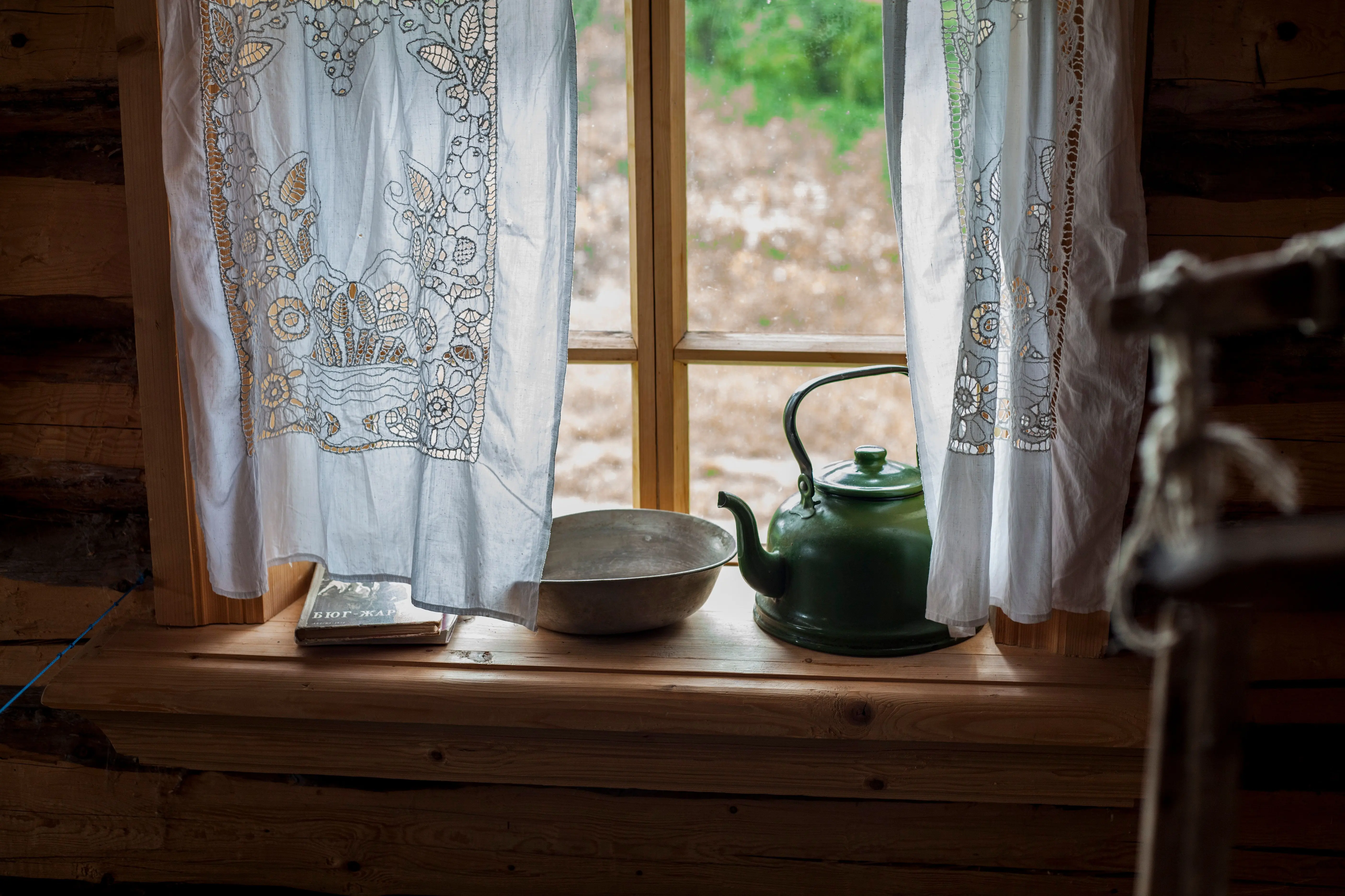 rustic wall art decor A cozy rustic windowsill with a green teapot and lace curtains overlooking the countryside.