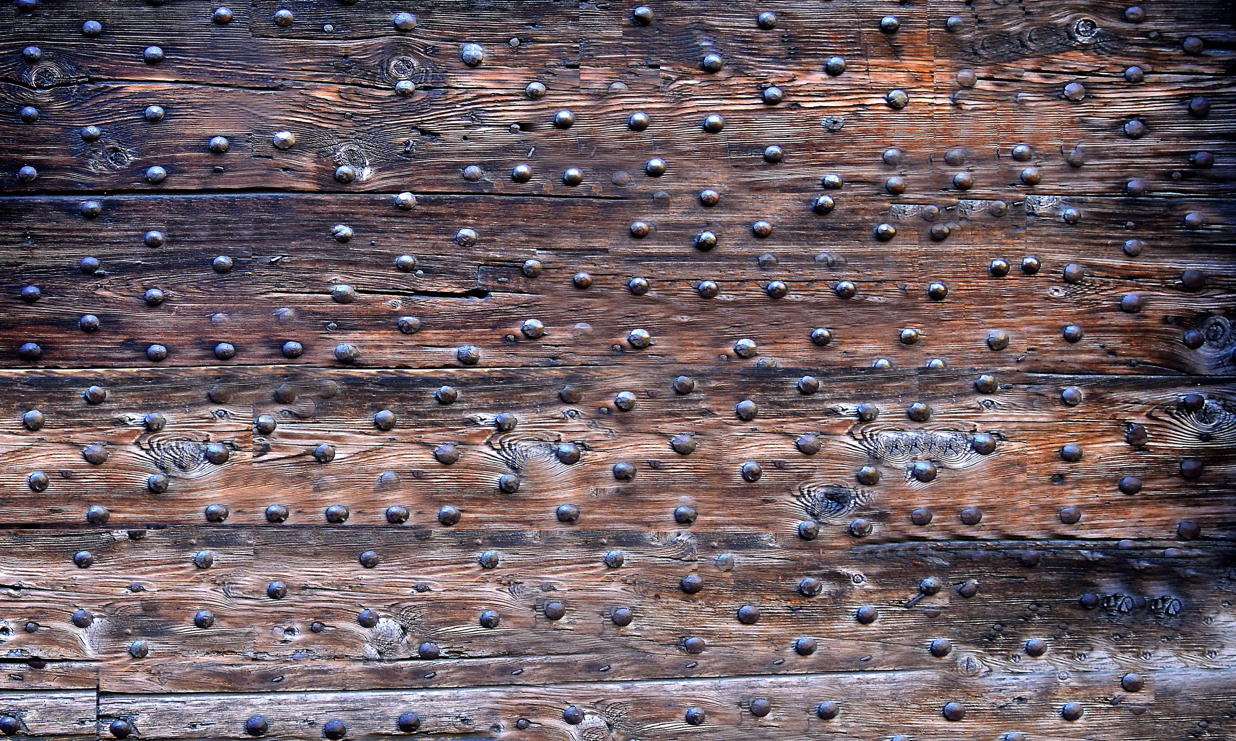 rustic wall art decor Close-up of an old wooden door with textured metal studs and rustic planks.