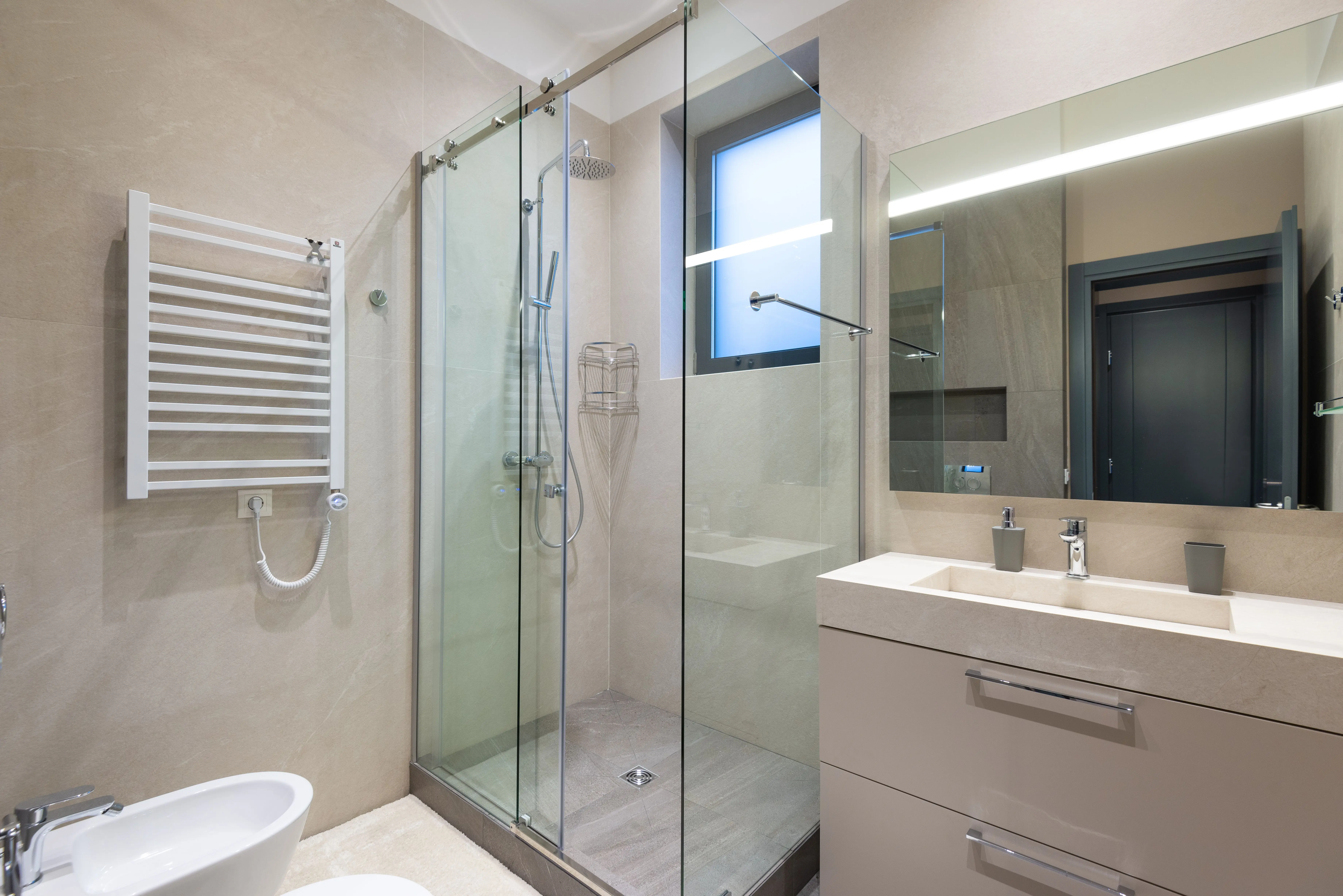 shower floors Shower cabin with glass walls near mirror hanging on wall above sink in modern minimalist styled bathroom