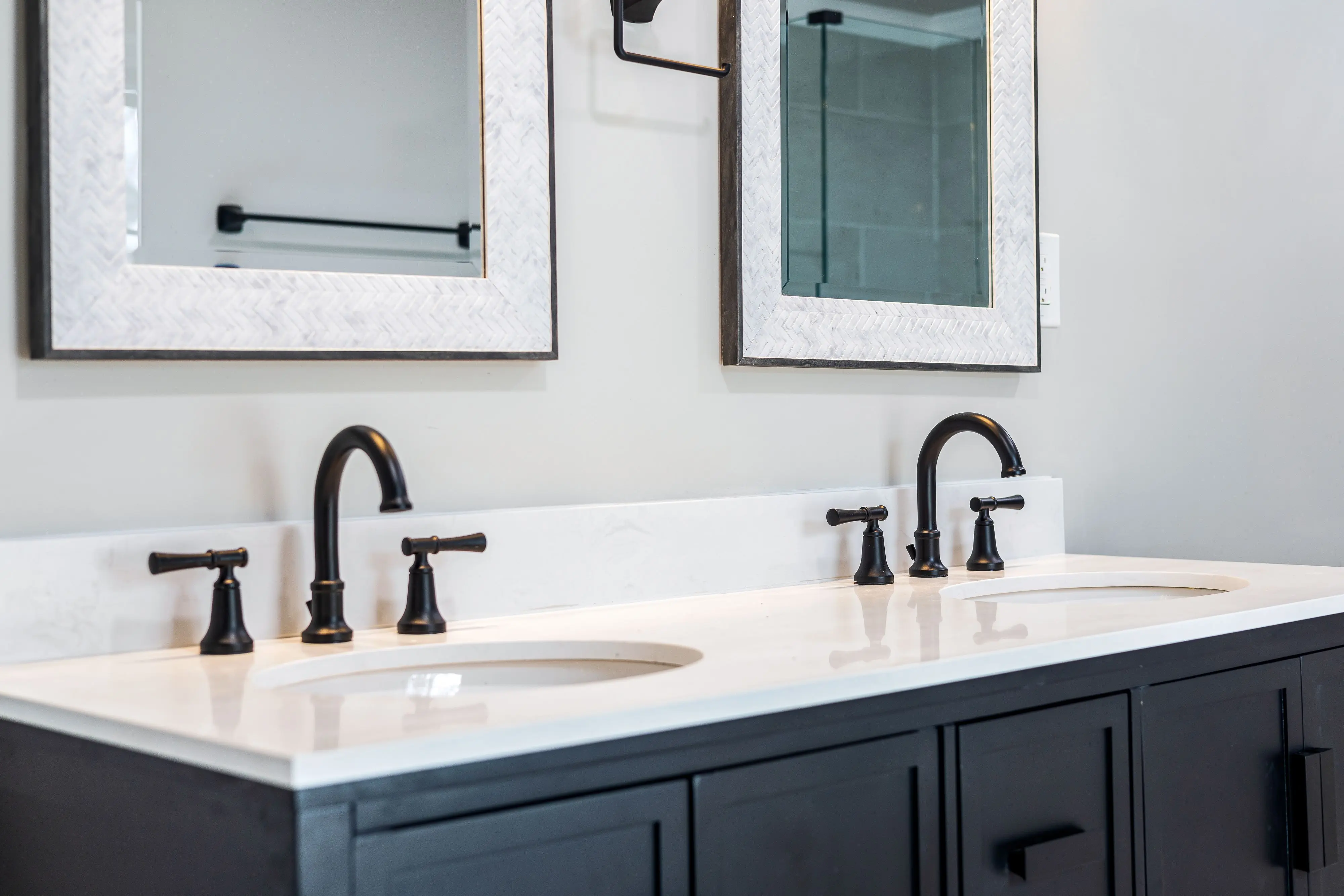 sink bath Sleek bathroom vanity featuring a double sink setup with stylish black faucets and framed mirrors.