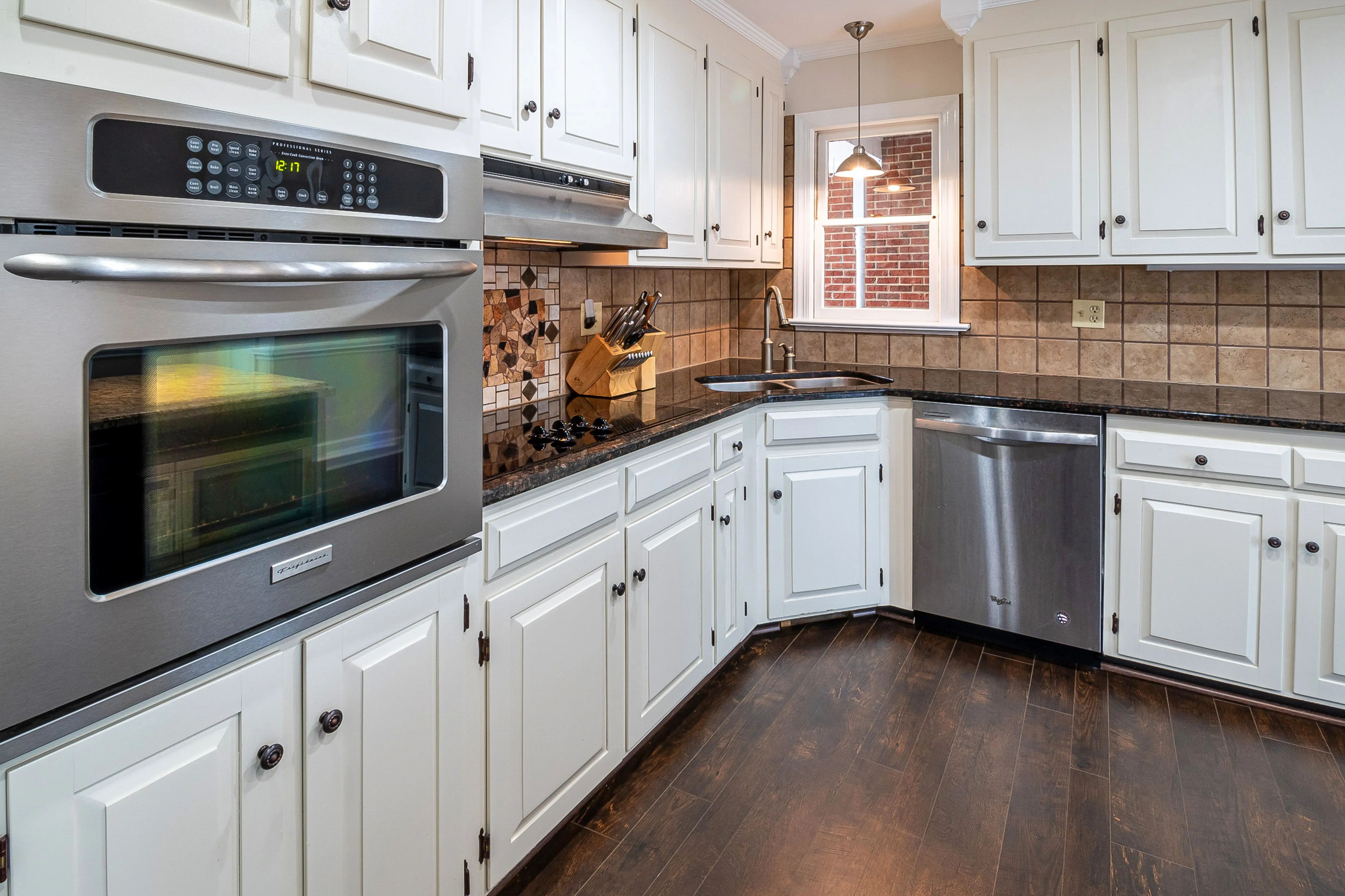 modern kitchen cabinet pulls Spacious kitchen featuring white cabinets, stainless steel appliances, and wooden flooring.