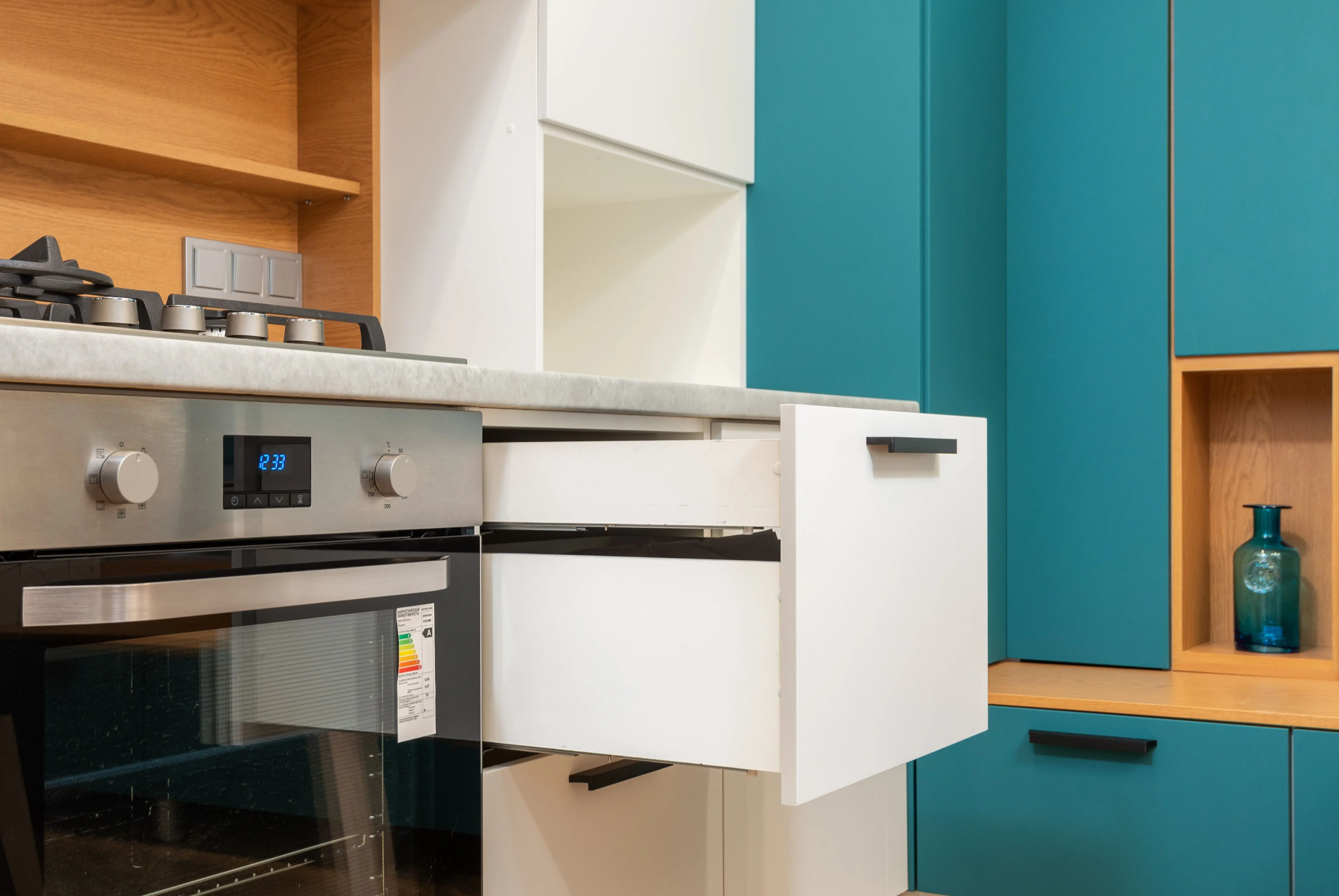 modern kitchen cabinet pulls Contemporary oven with sticker and gas stove under wooden shelves in kitchen with open drawer