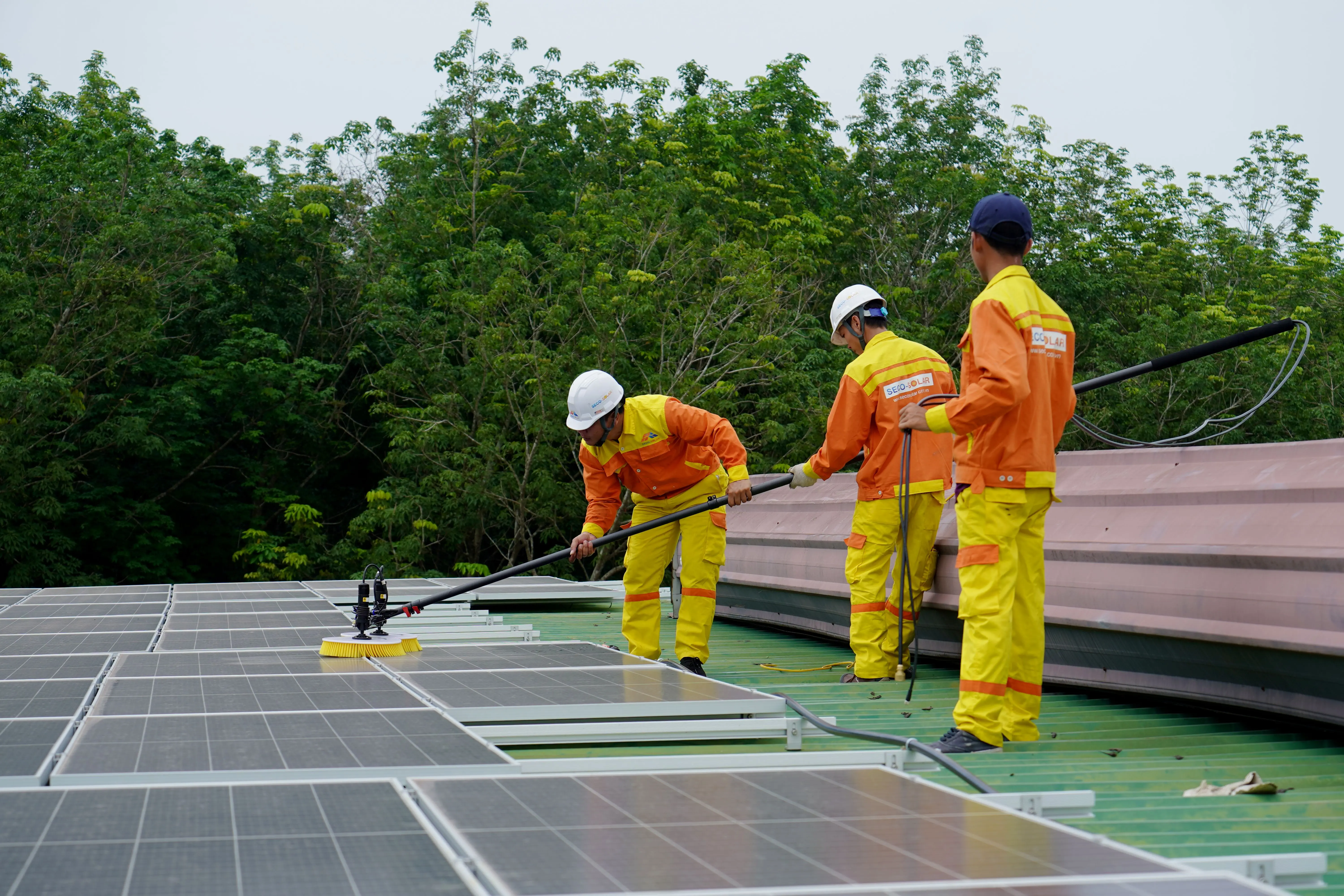 solar powered bird bath Three technicians in uniforms and hardhats clean rooftop solar panels in a renewable energy project.