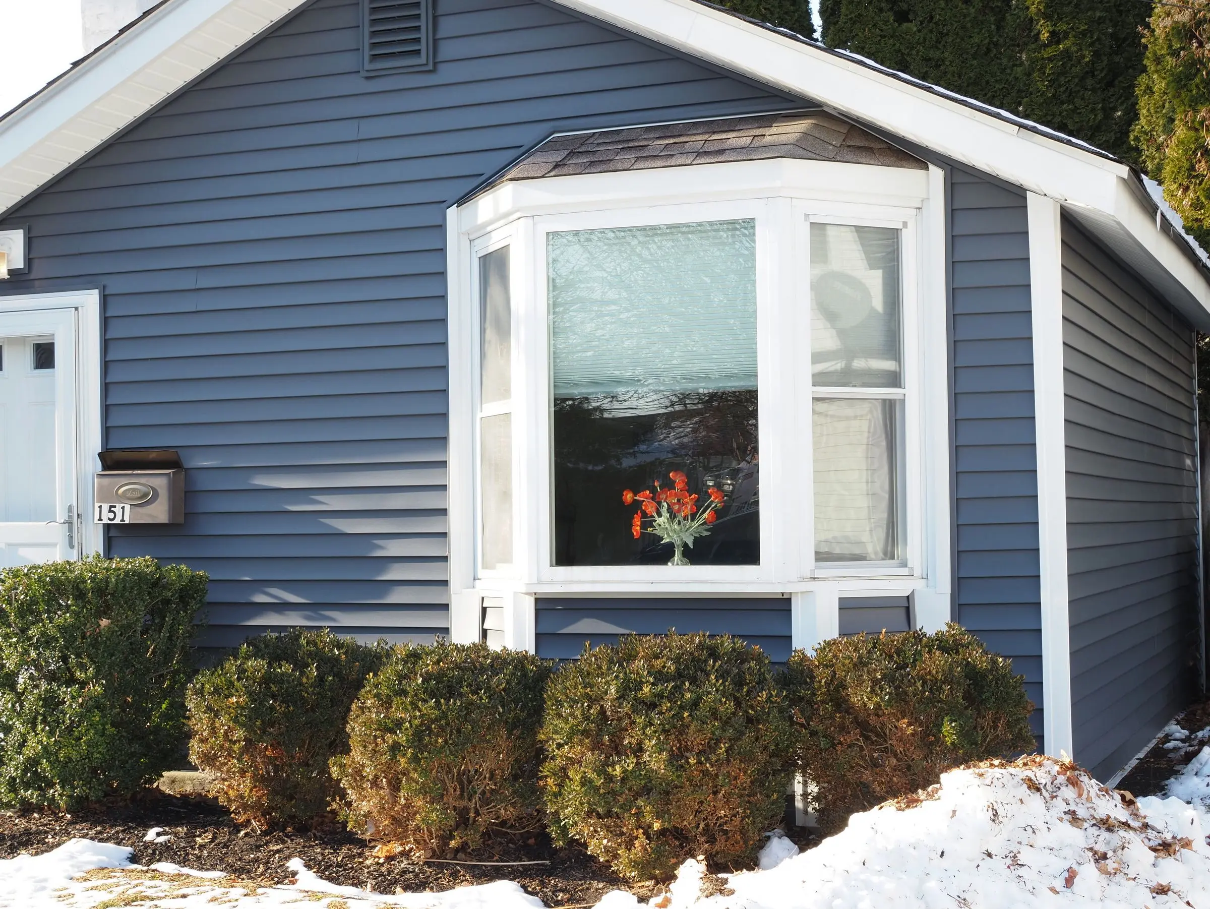 house siding ideas Cozy blue house with a bay window and snow in Doylestown, PA.