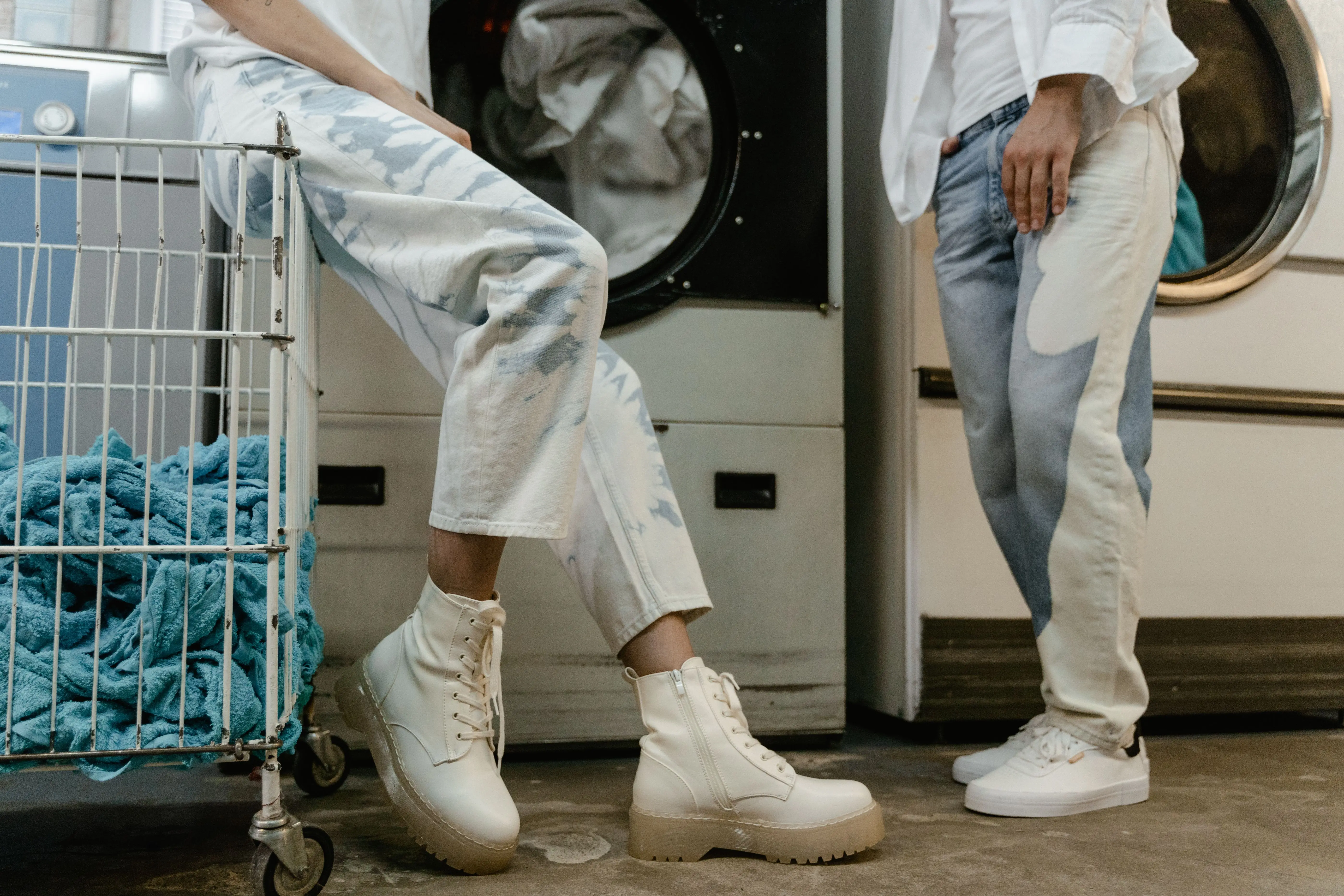 how to get blood out of denim Two people wearing trendy outfits in a modern laundry facility, showcasing casual fashion.