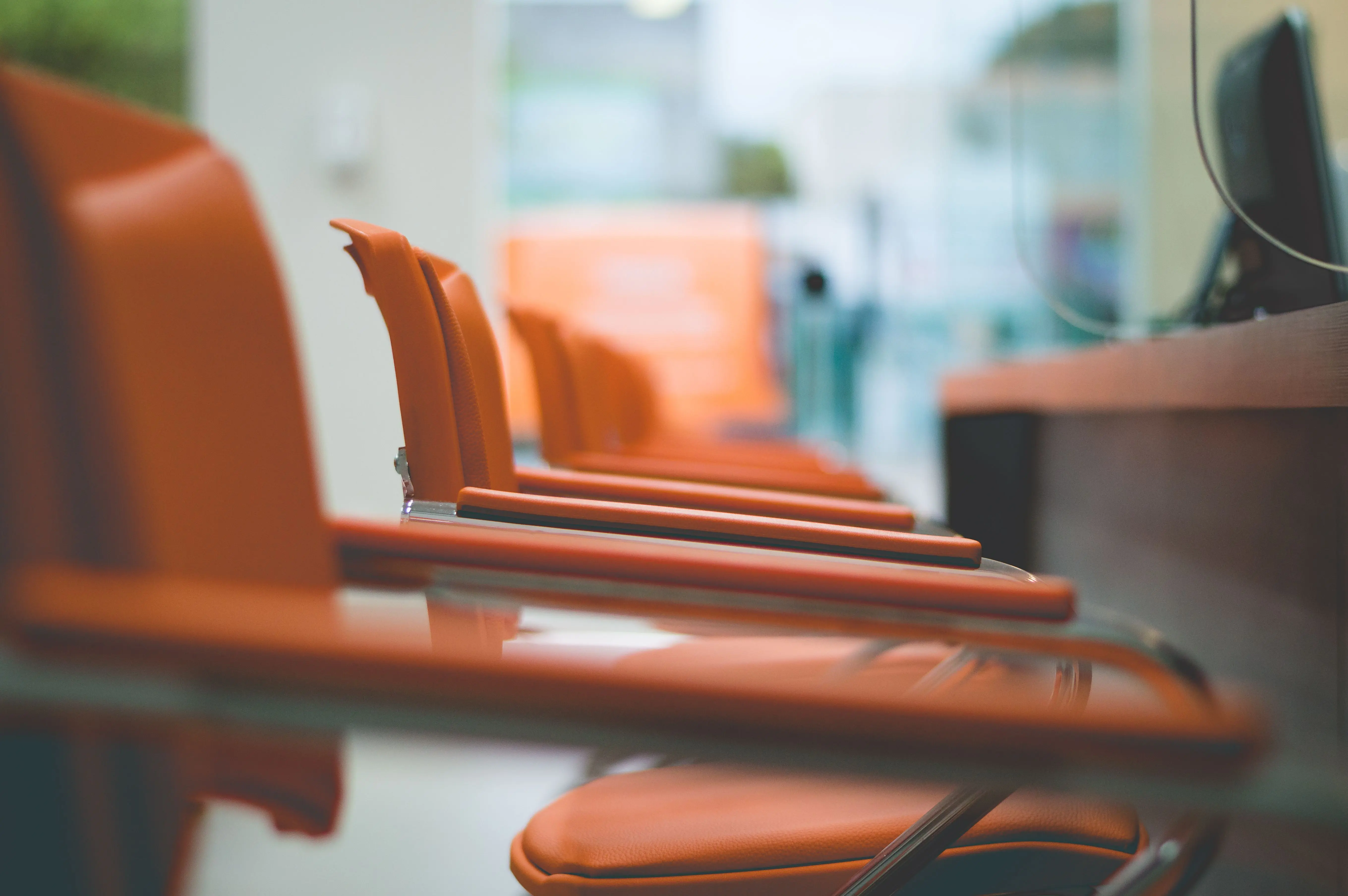 secondary furniture grouping Close-up of sleek orange office chairs in a waiting area with focus on design.