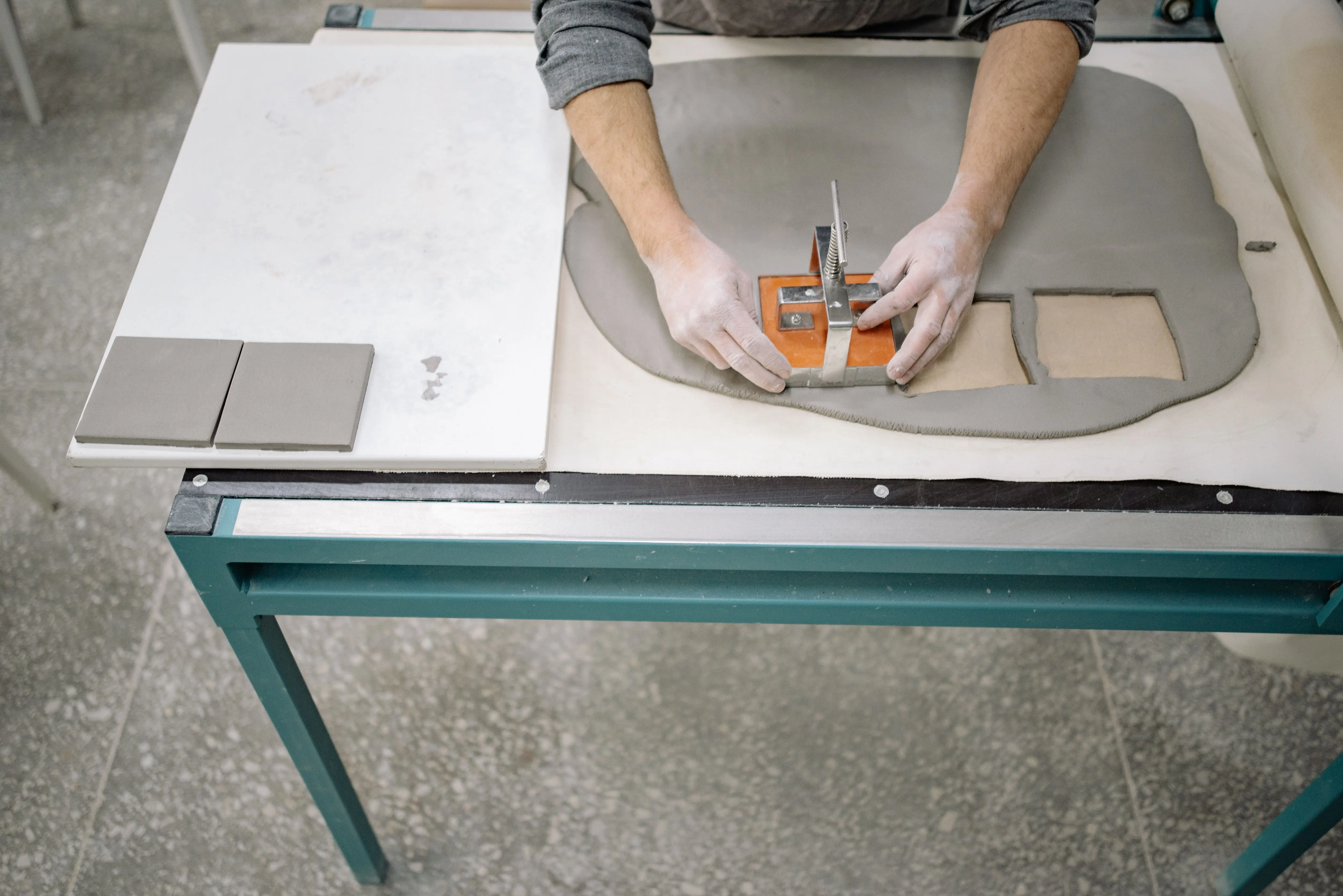 tiling glass tiles A person shaping clay using a cutter to craft tiles on a worktable.