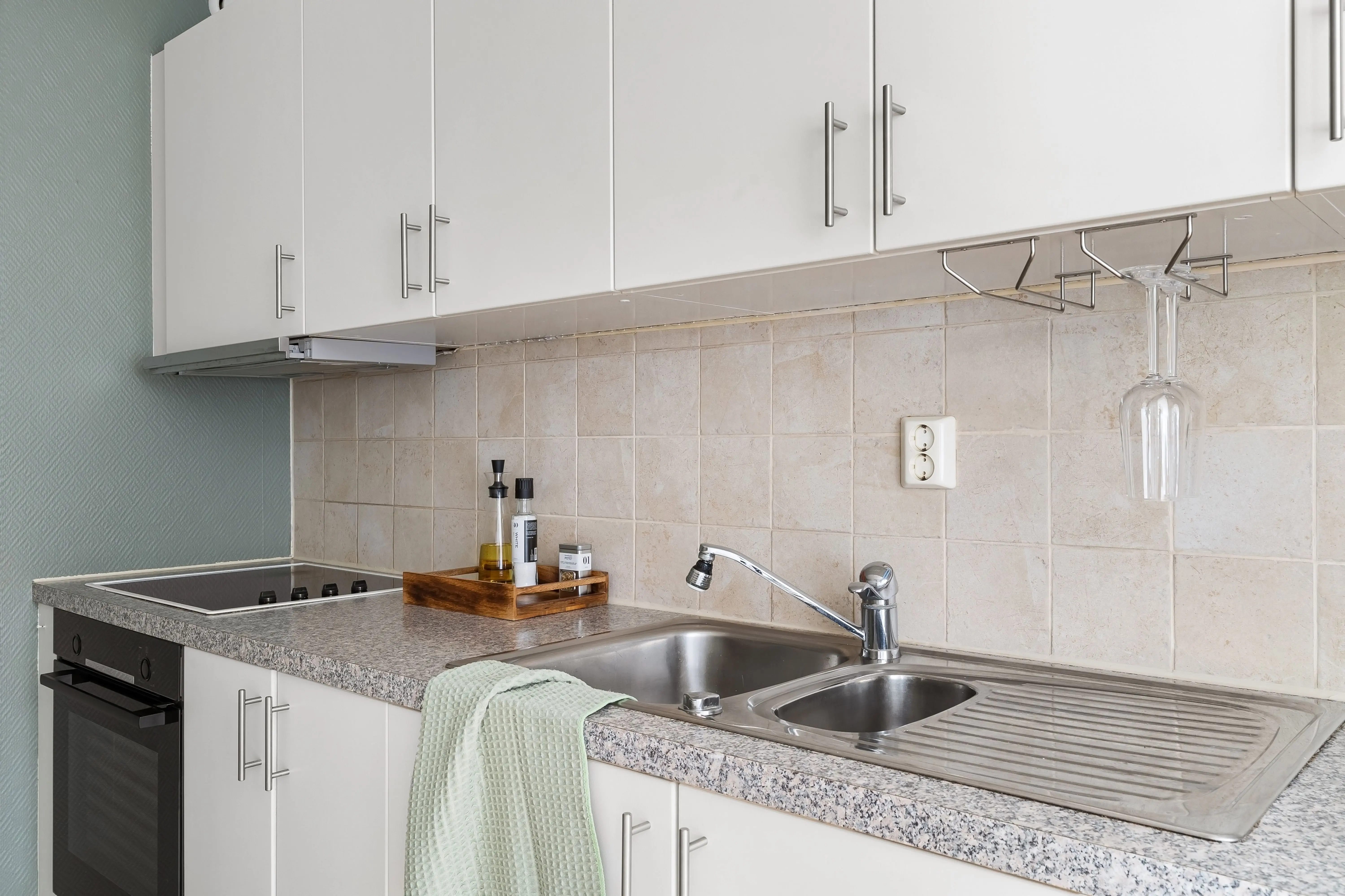 green granite Sleek modern kitchen with granite countertops, stainless steel sink, and white cabinets.