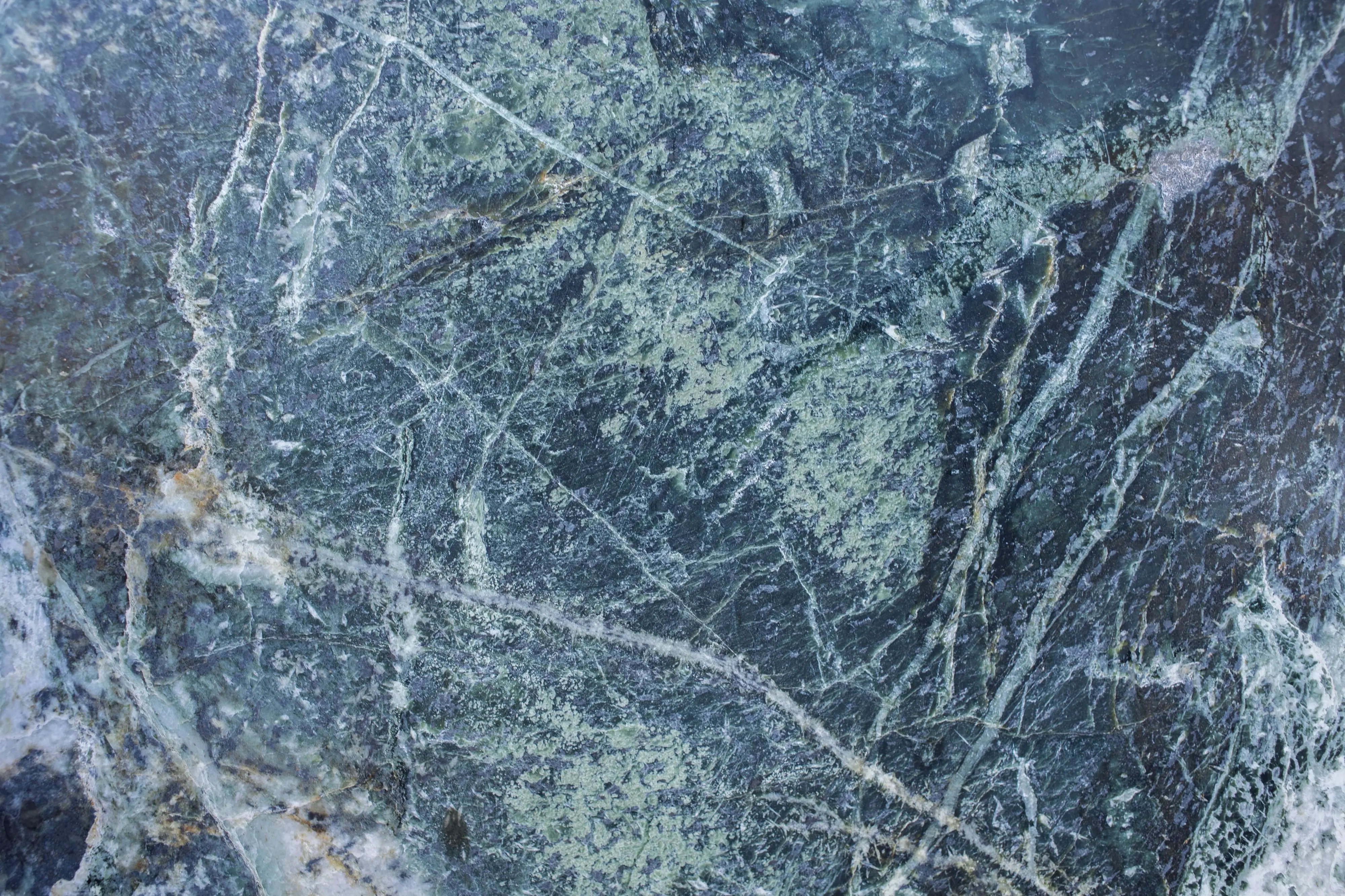 green granite Textured backdrop representing rough uneven blue surface of stone rock with white spots and lines