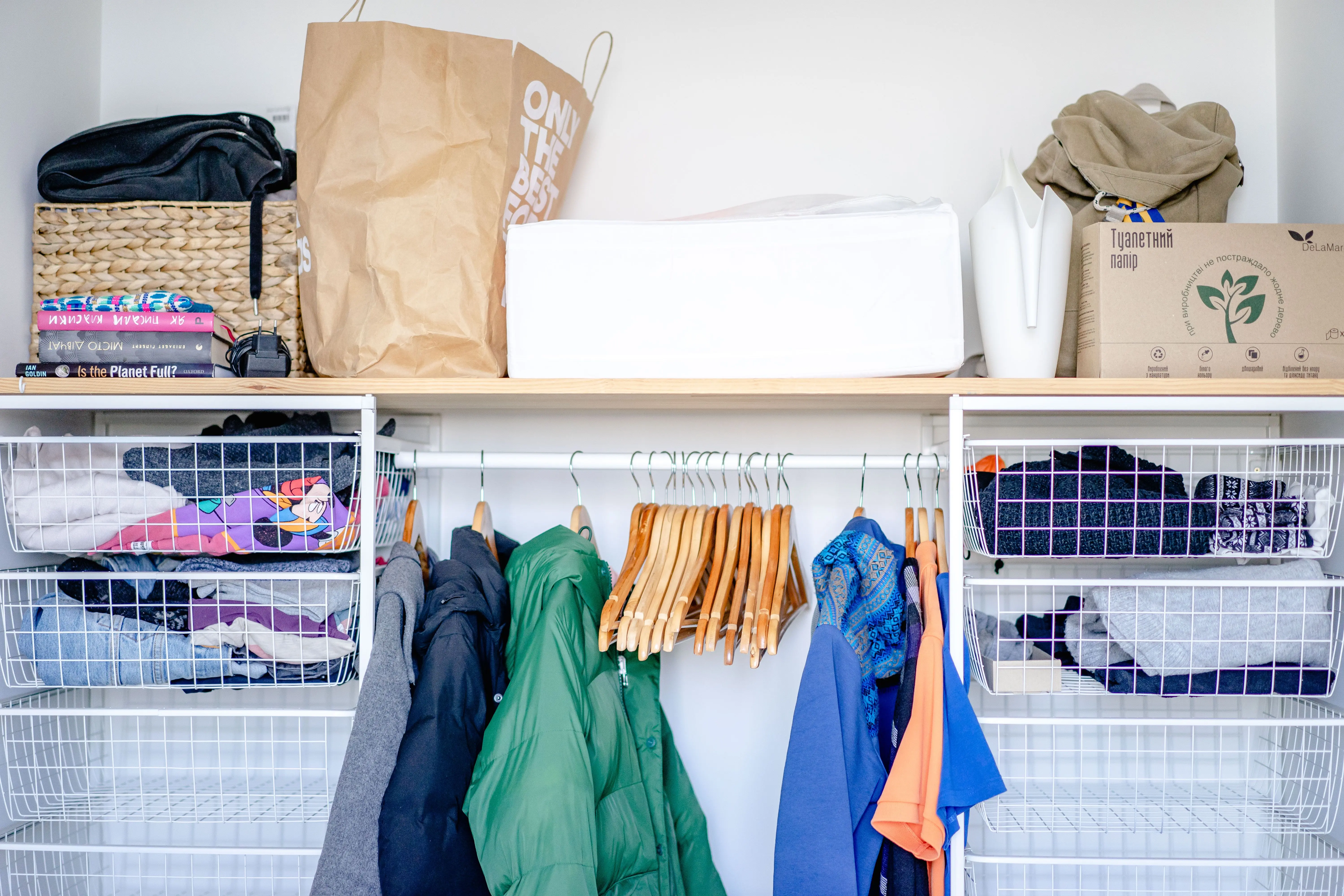 messy house A minimalist open wardrobe featuring modern clothing, hangers, and storage baskets.