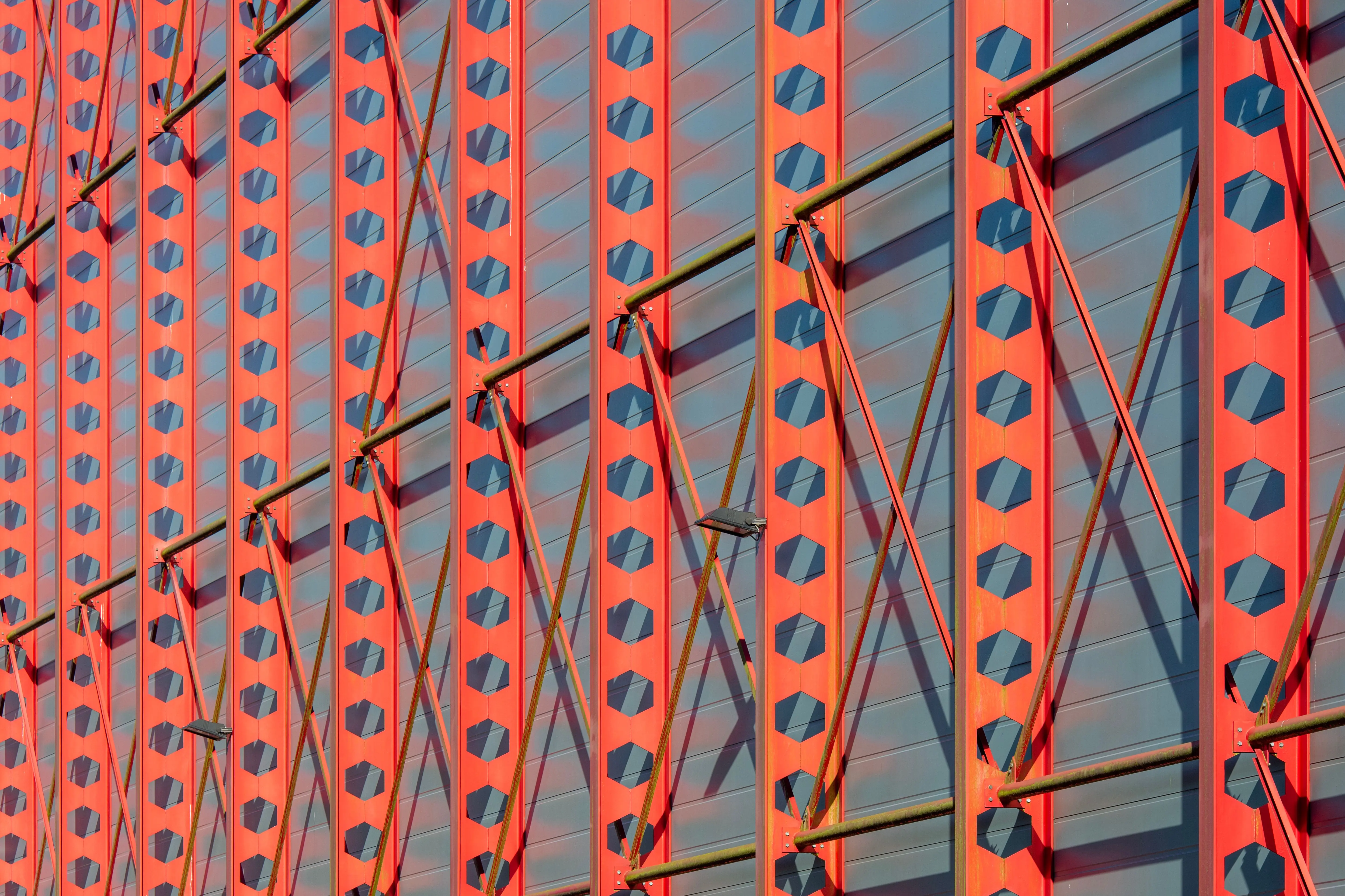 large exterior metal wall art Close-up view of a modern red steel facade with a geometric pattern, showcasing urban architectural design.