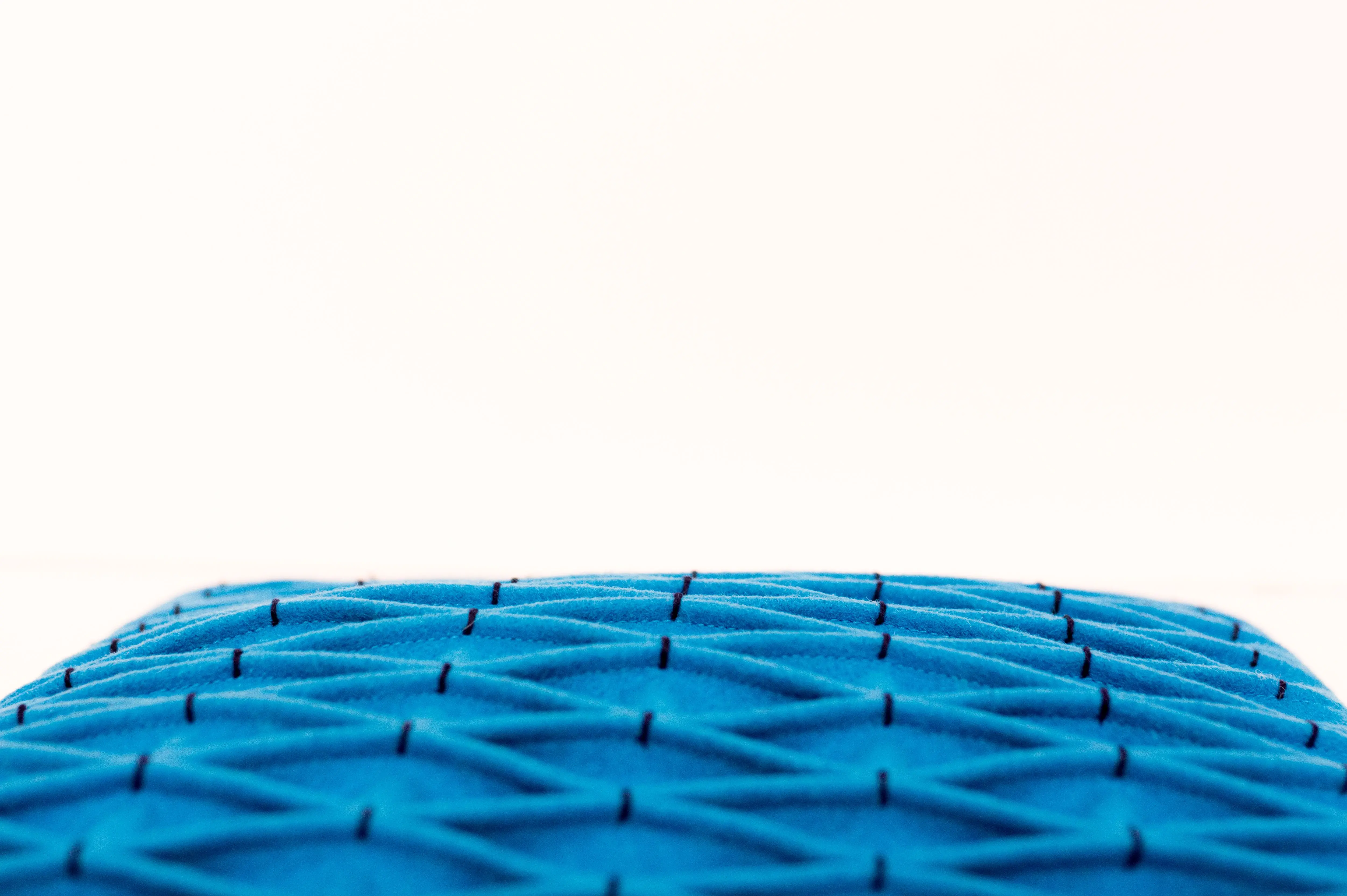 lumbar pillow covers A minimalist photo featuring a close-up of a blue textured fabric pillow against a neutral background.