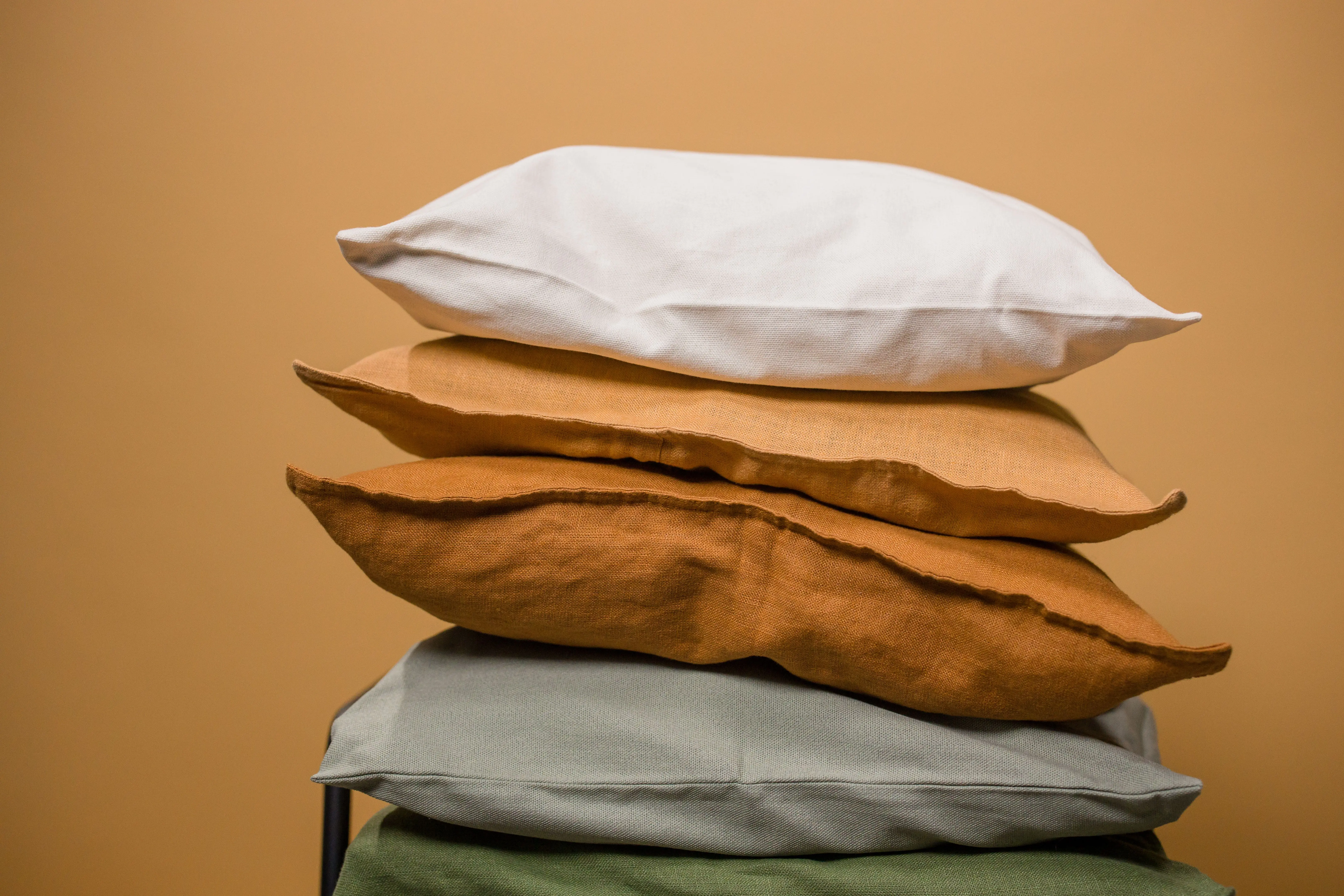 lumbar pillow covers Stack of different colorful pillows folded and placed in stack on chair isolated on dark beige background