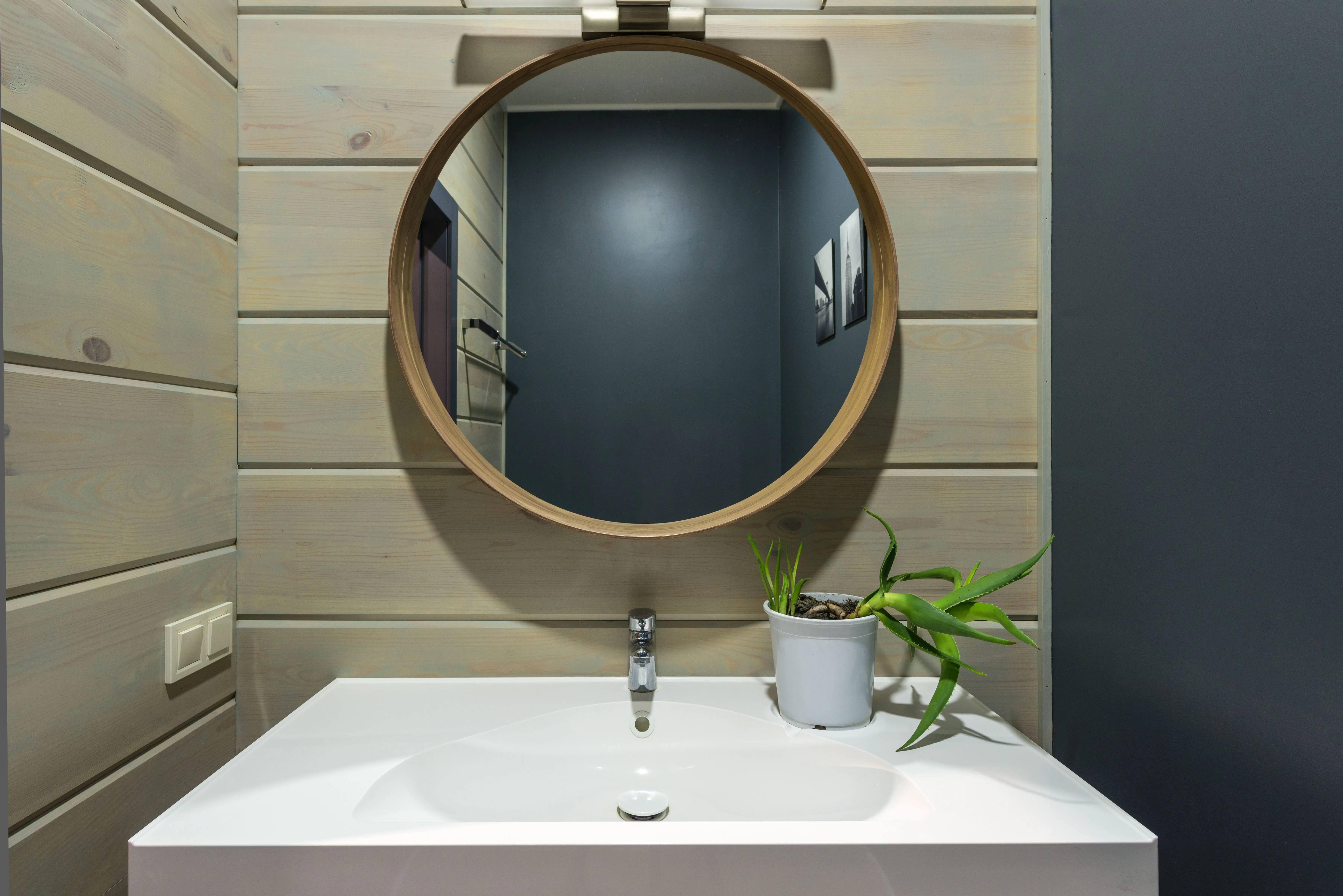 small master bathroom designs Round mirror hanging above sink with faucet and potted plant on wall made of panels in modern bathroom