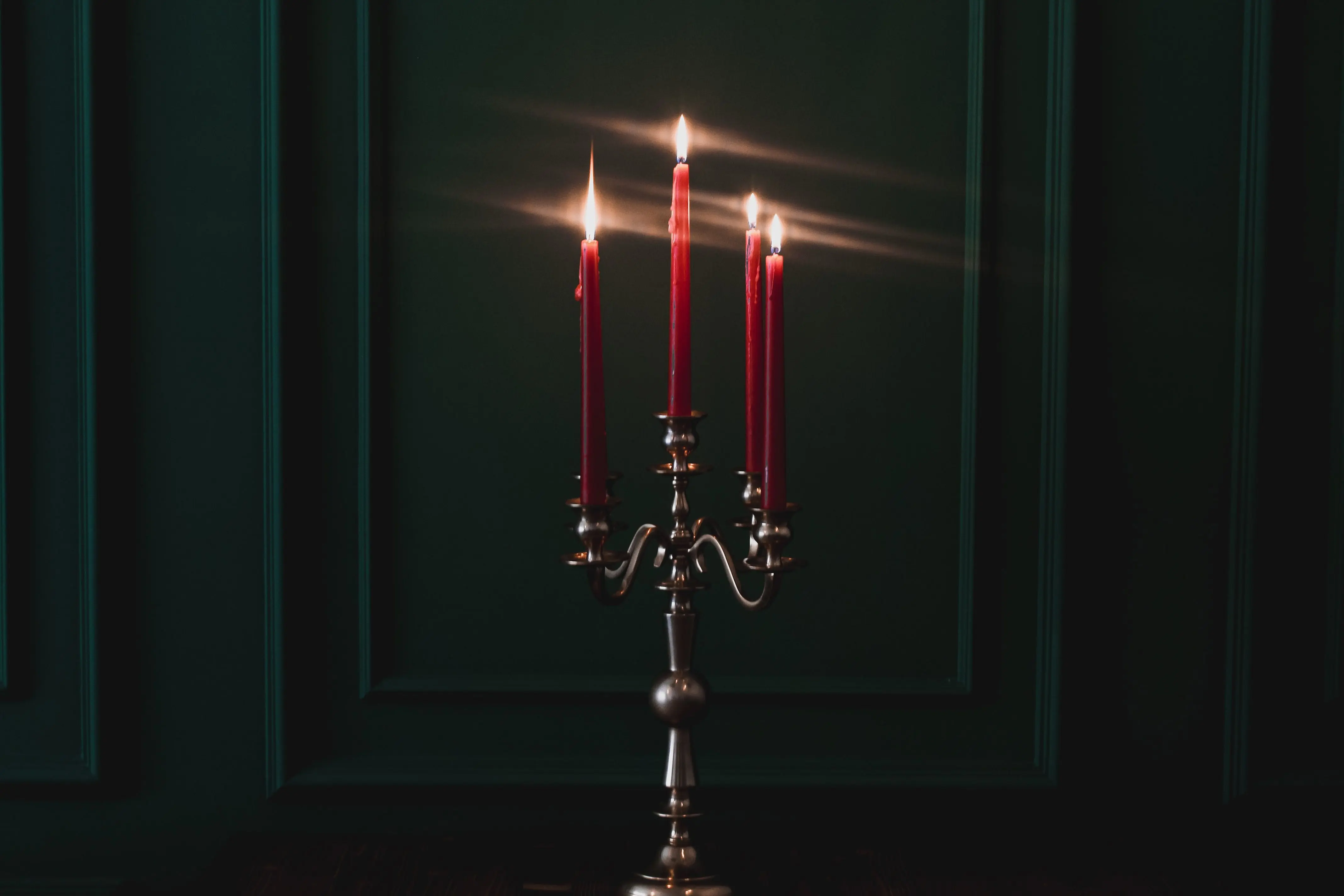 tapered candle holders Elegant red candles on a silver candelabra set in a dark room, creating a warm ambiance.