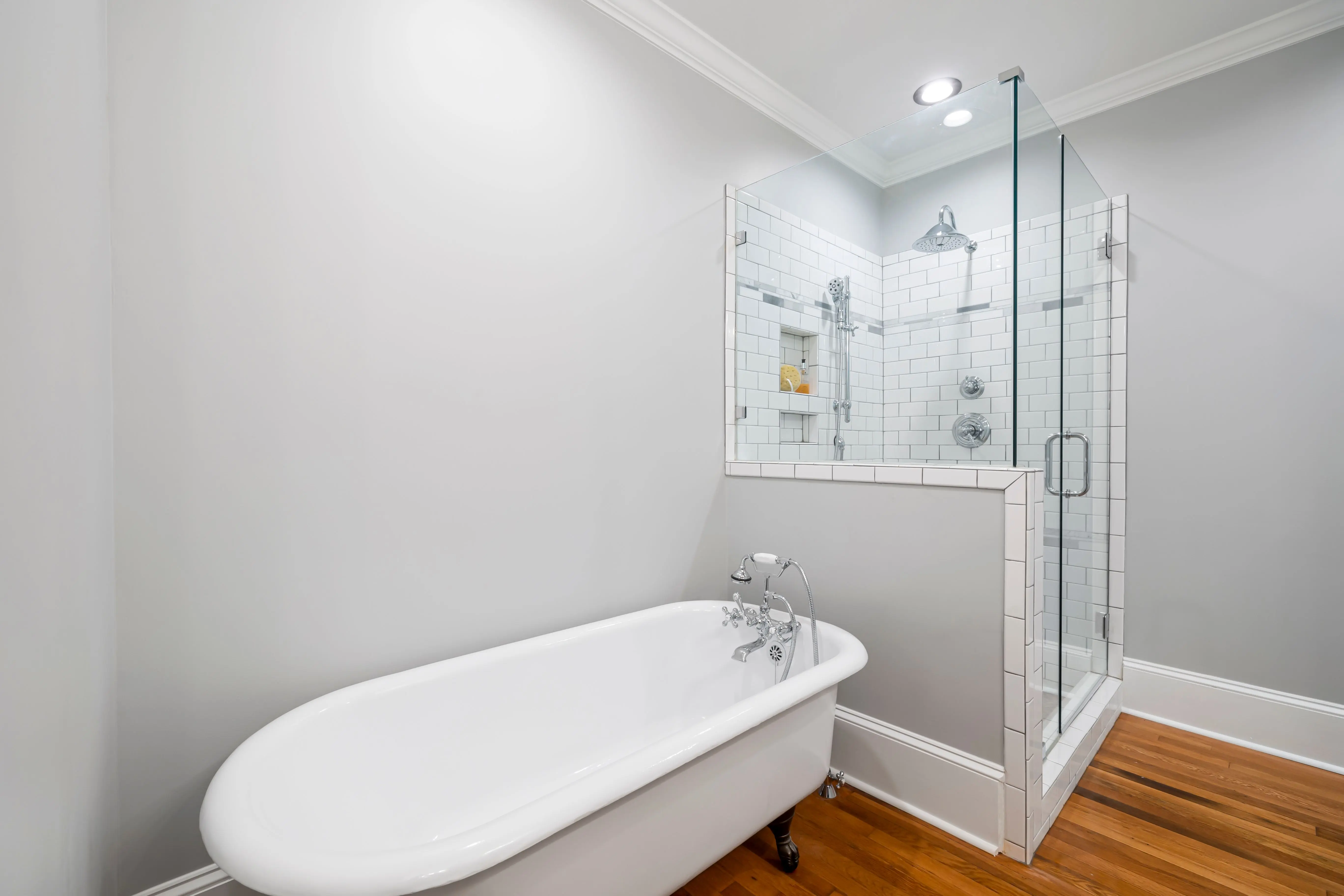 tub inside shower Modern minimalist bathroom featuring a luxurious clawfoot bathtub and a sleek glass-enclosed shower.