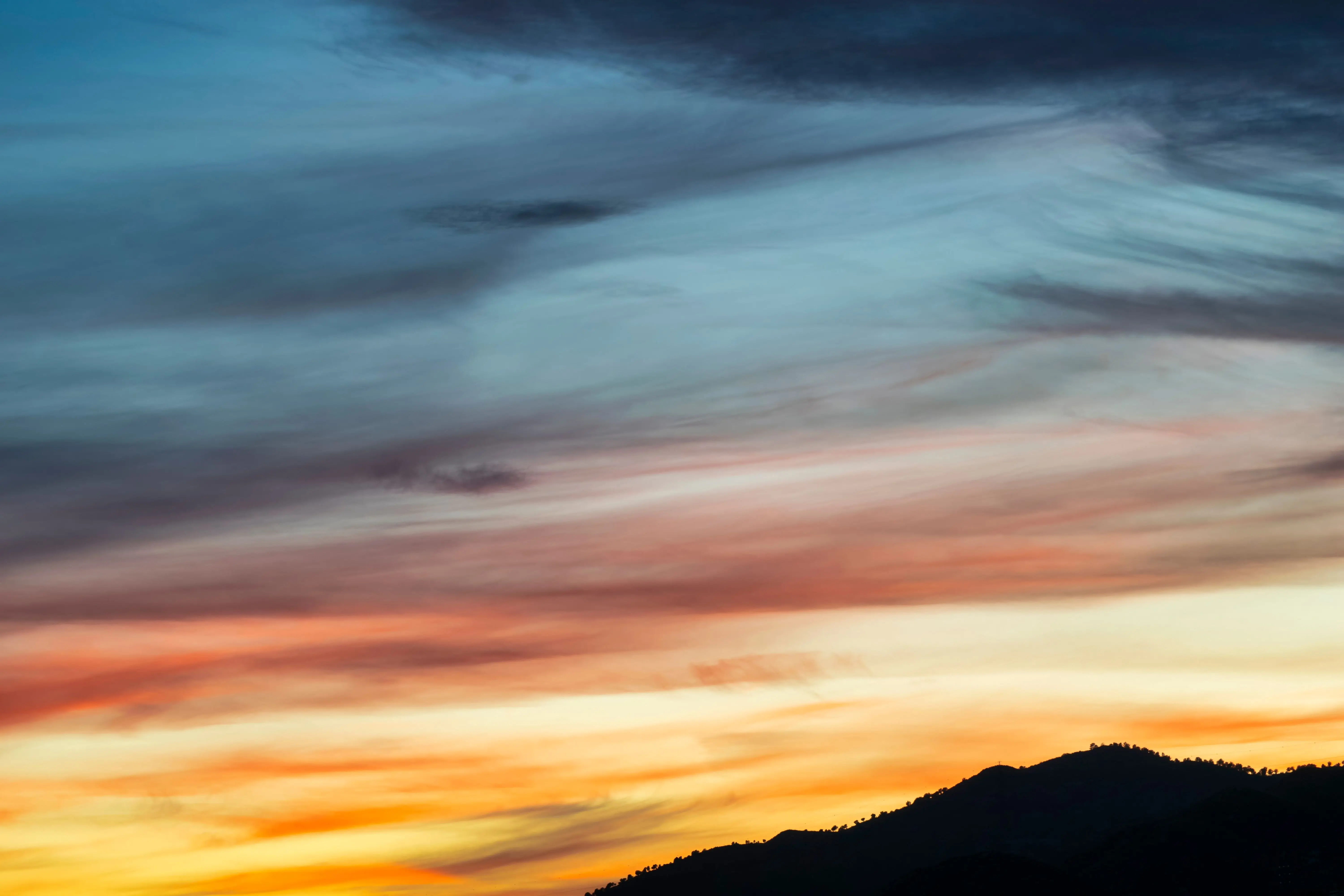 paint inspo A vibrant sunset with colorful clouds over silhouetted hills, perfect for nature enthusiasts.