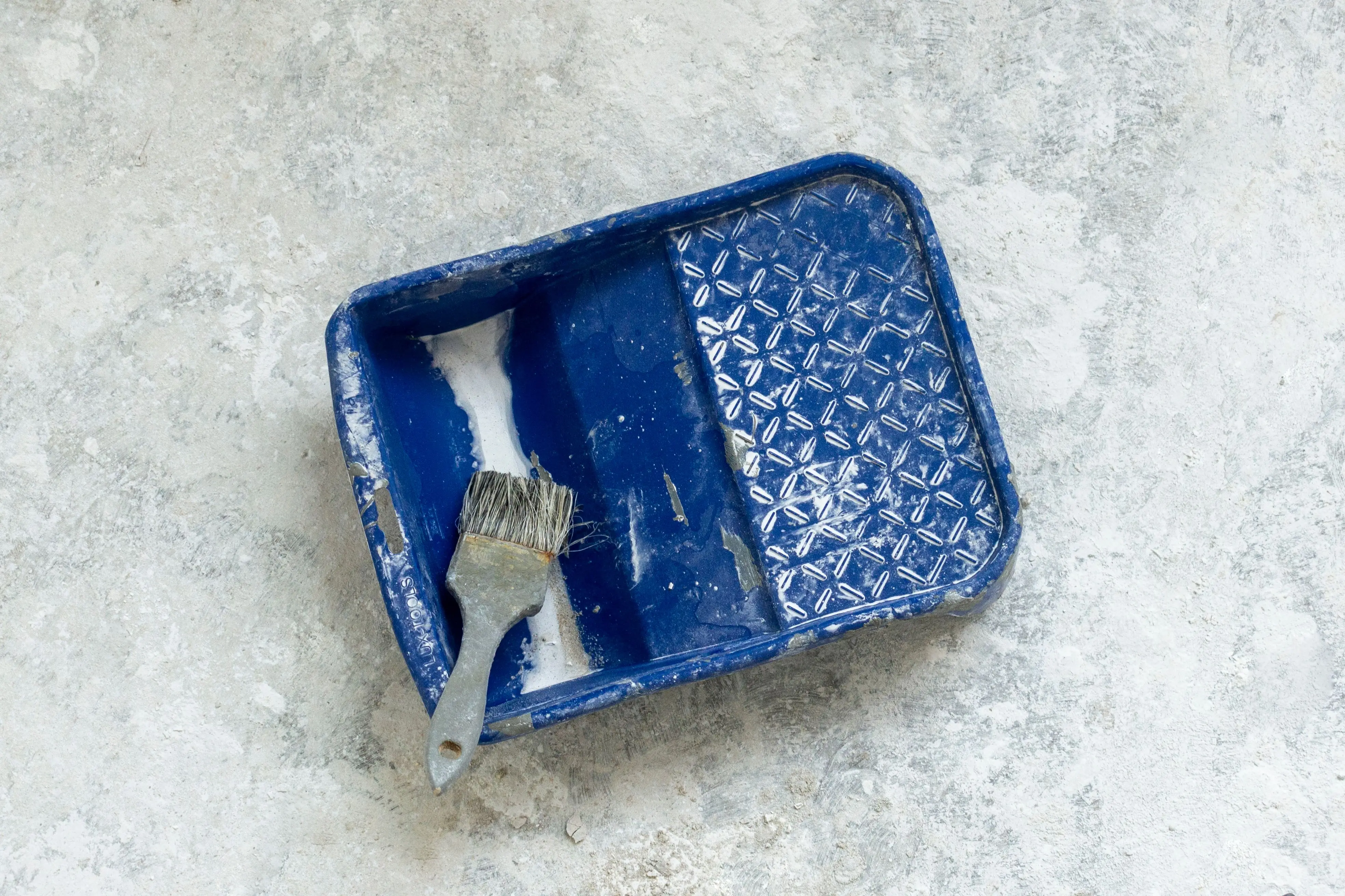 paint trays Stock photo of a well-used blue paint tray and brush on a textured surface, perfect for renovation themes.