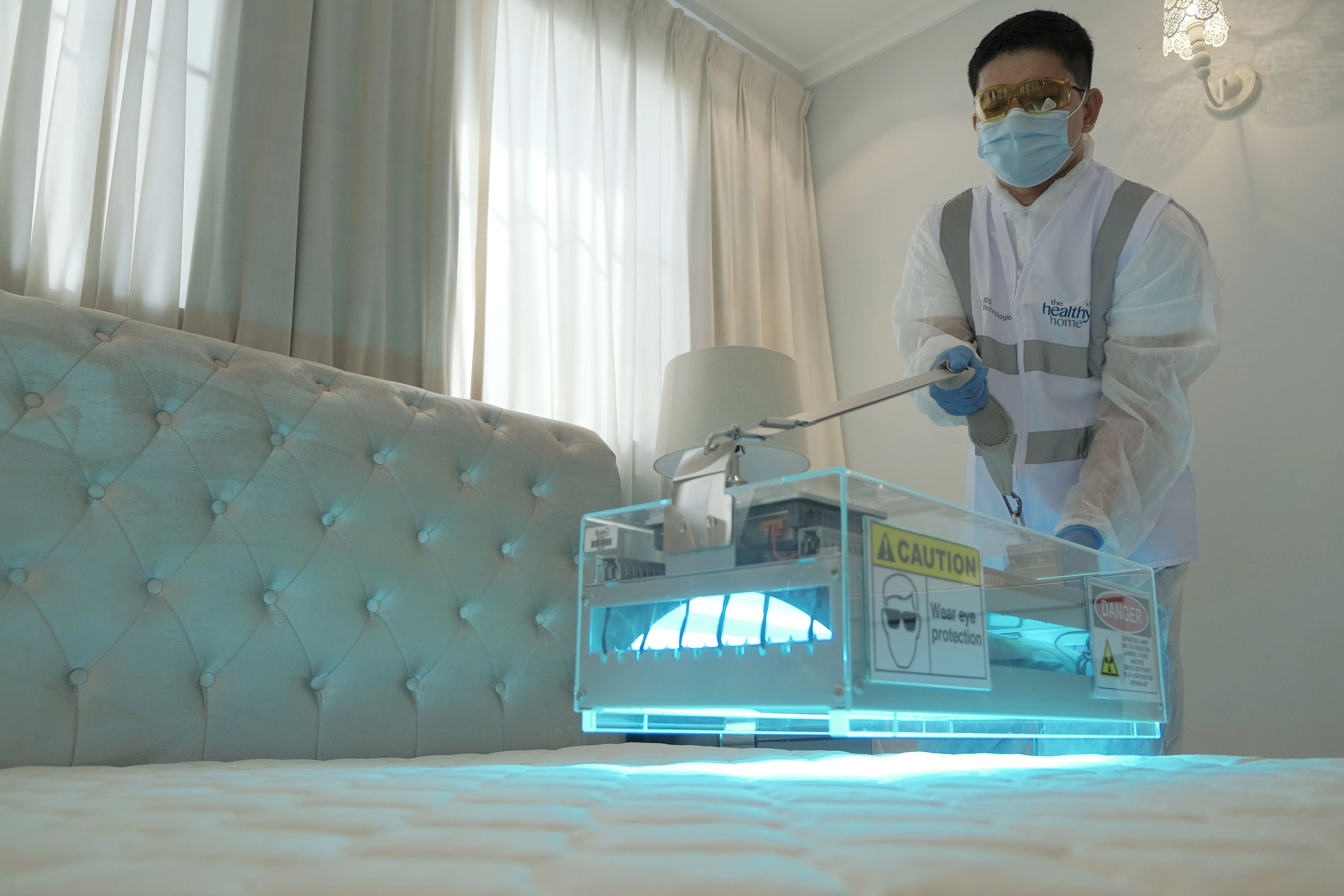tiny beetles in house Technician sanitizing hotel room bed with UV light for safe and clean environment.