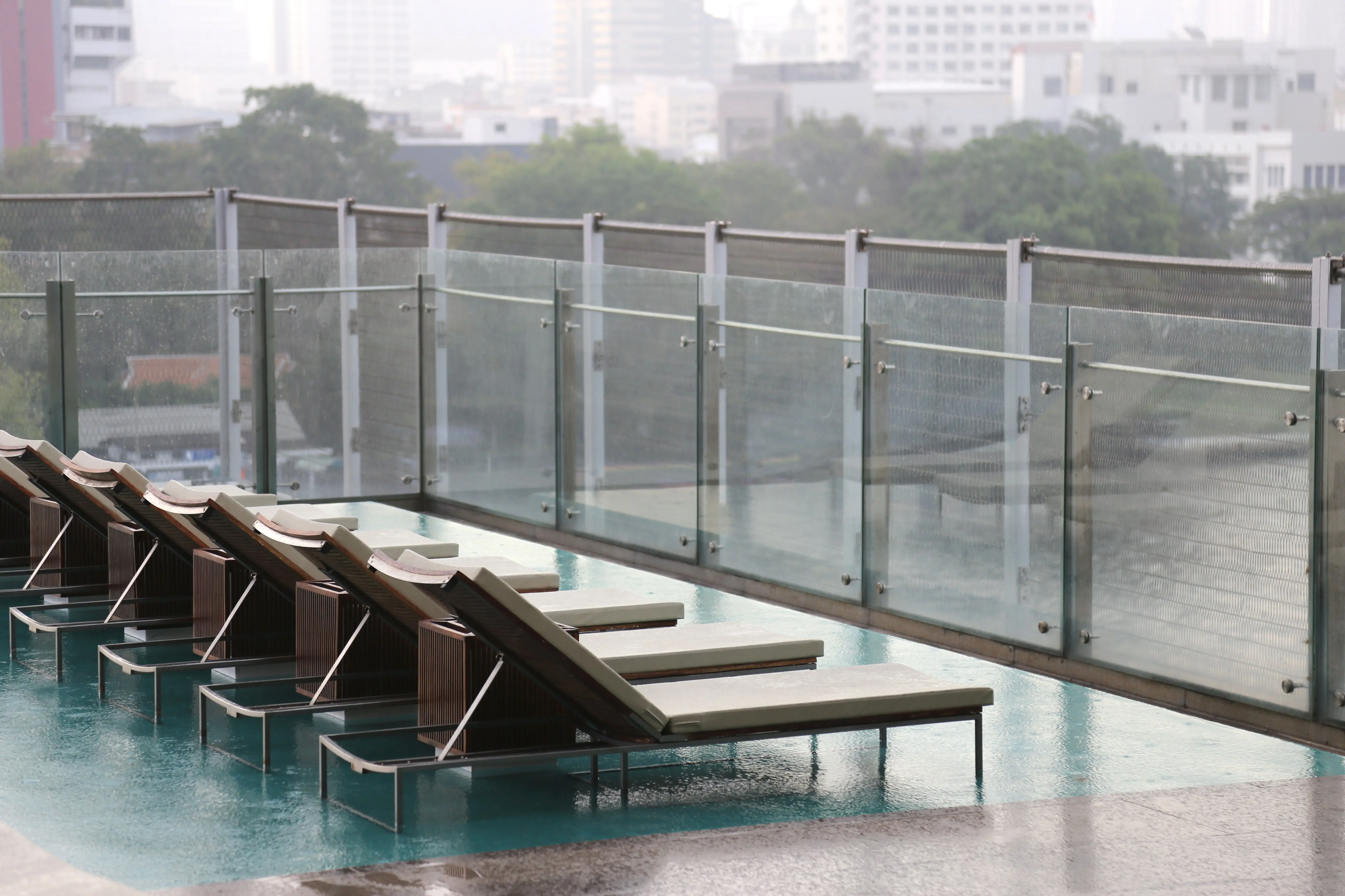 pool gates Modern urban terrace with sunbeds beside a pool, featuring glass railings.