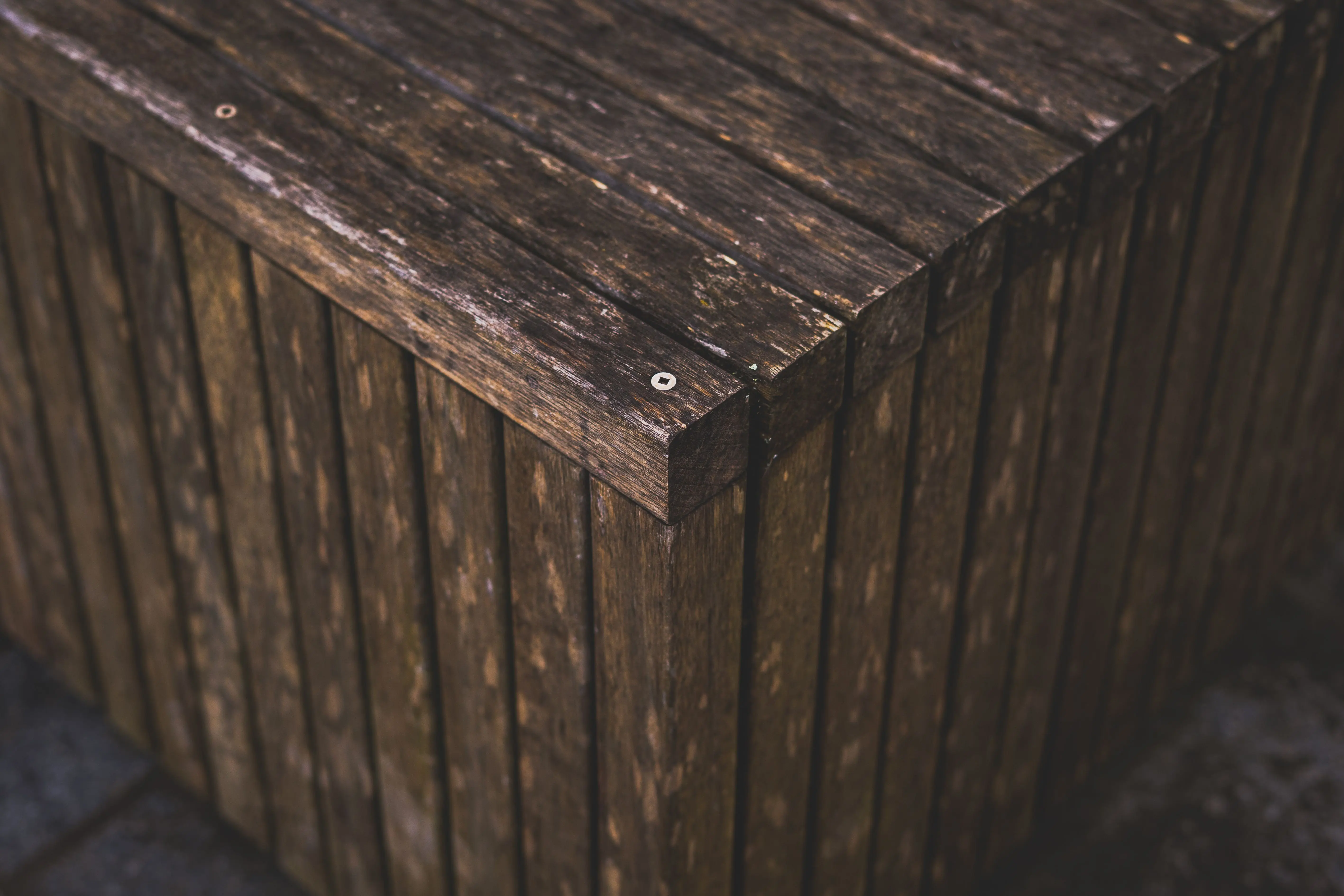 rustic cabinets Detailed view of a weathered wooden structure with textured slats and metal screws.