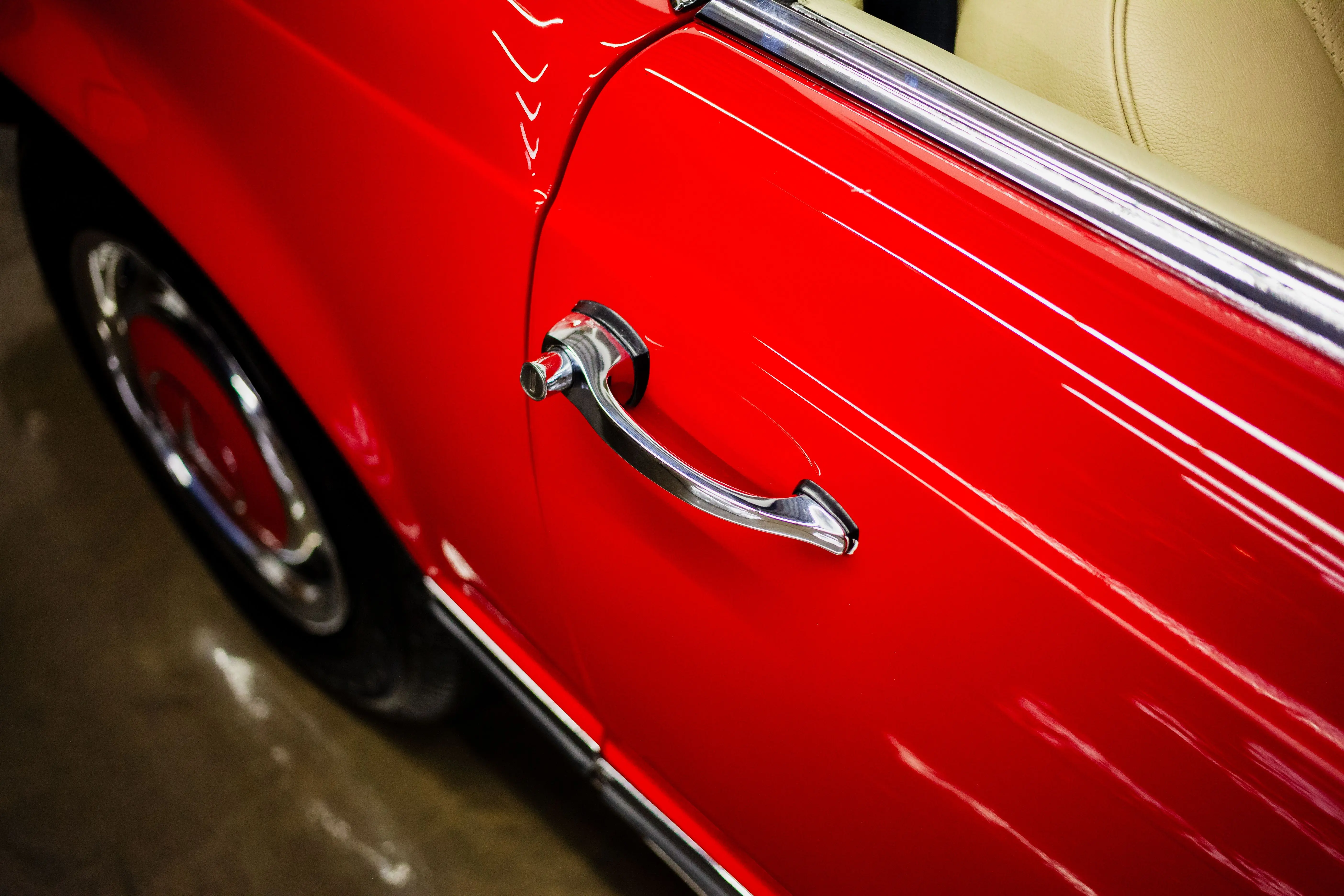 how to fix paint chips on car Detailed shot of a classic car's red door and chrome handle captured indoors.
