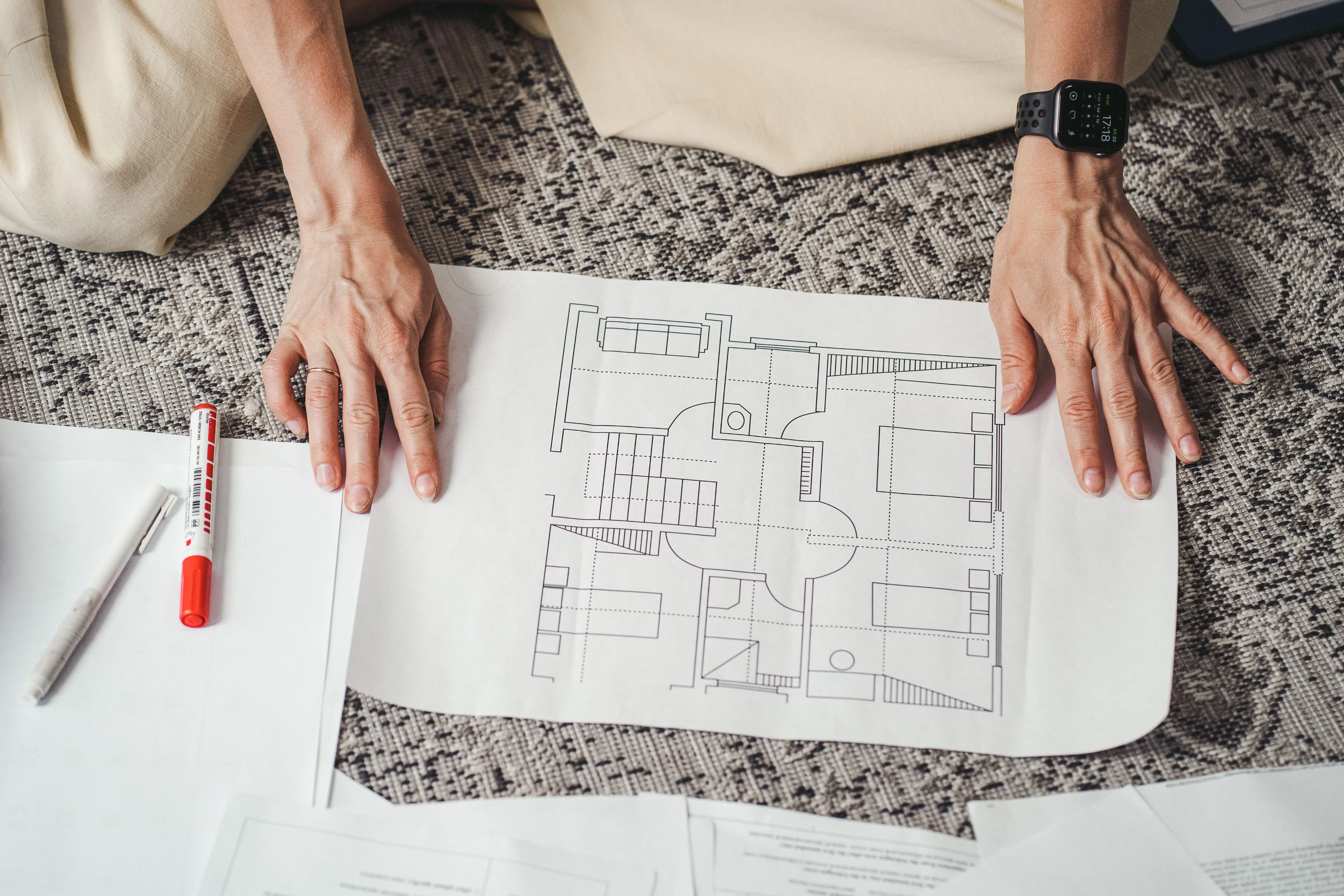 siding installation cost Hands on a detailed architectural floor plan paper, showcasing home design layout.