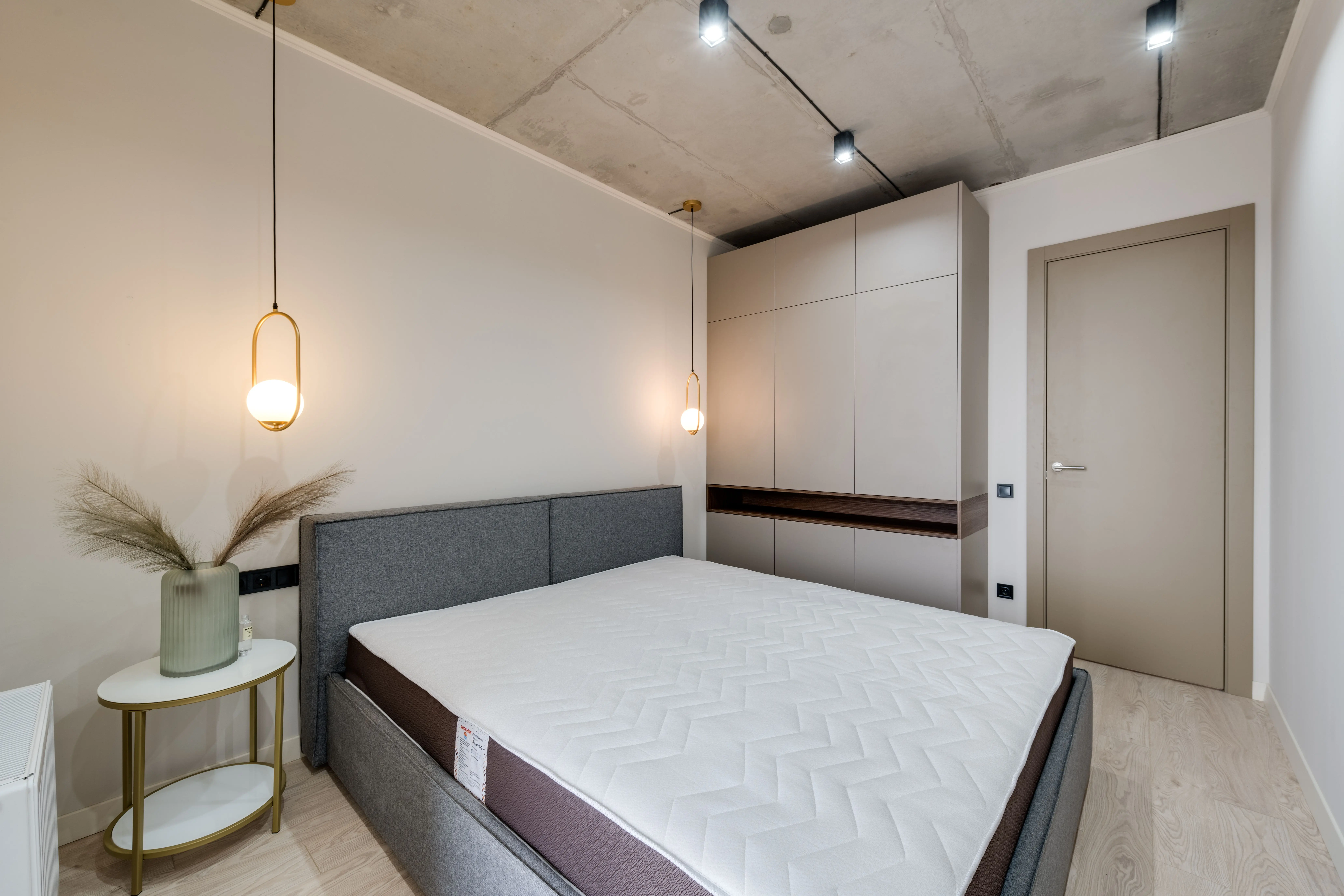 paint inspo A minimalist bedroom featuring a gray bed, warm lighting, and sleek storage solutions.