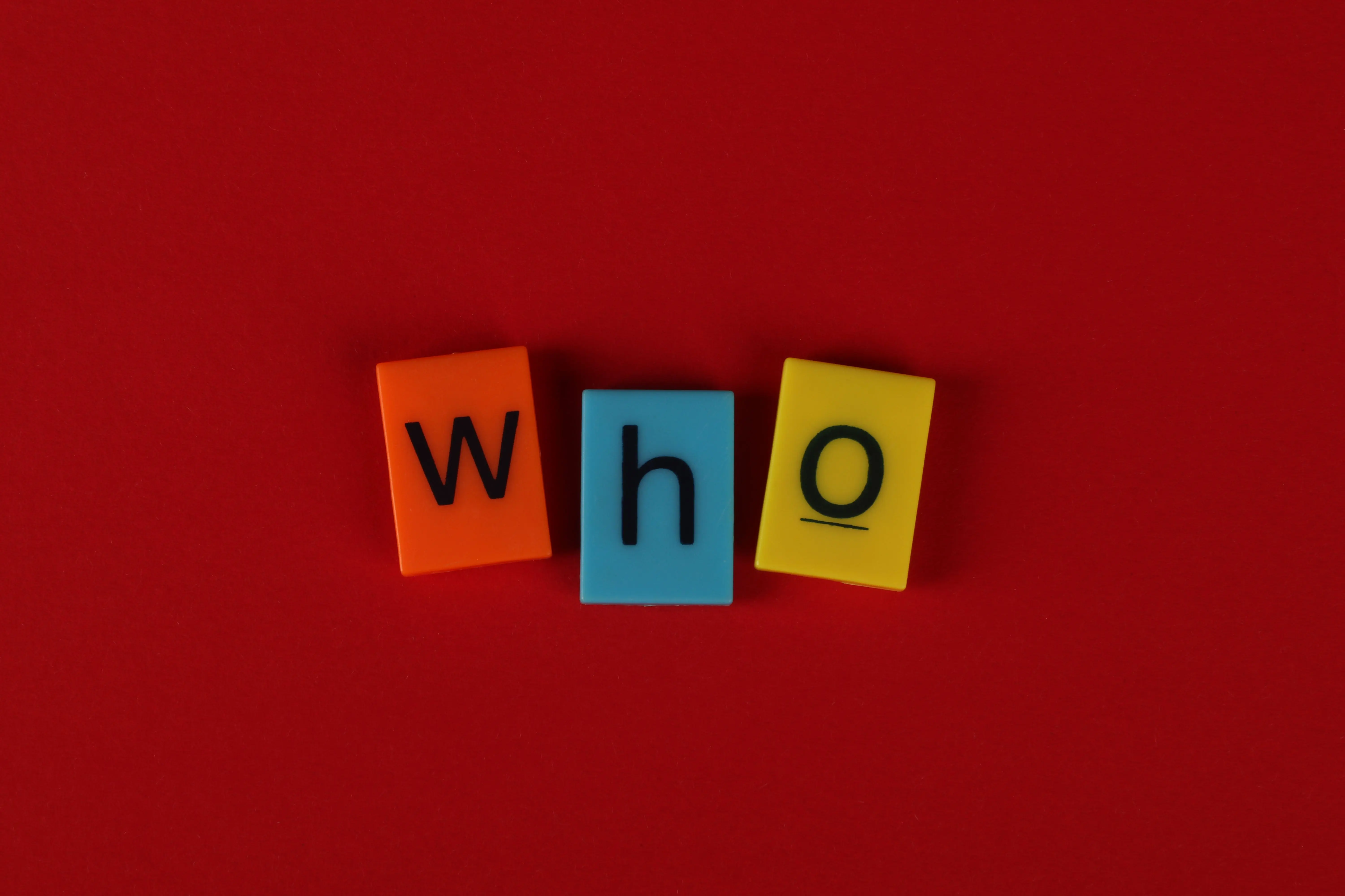 tiling glass tiles Alphabet blocks forming the word 'who' against a vibrant red backdrop.
