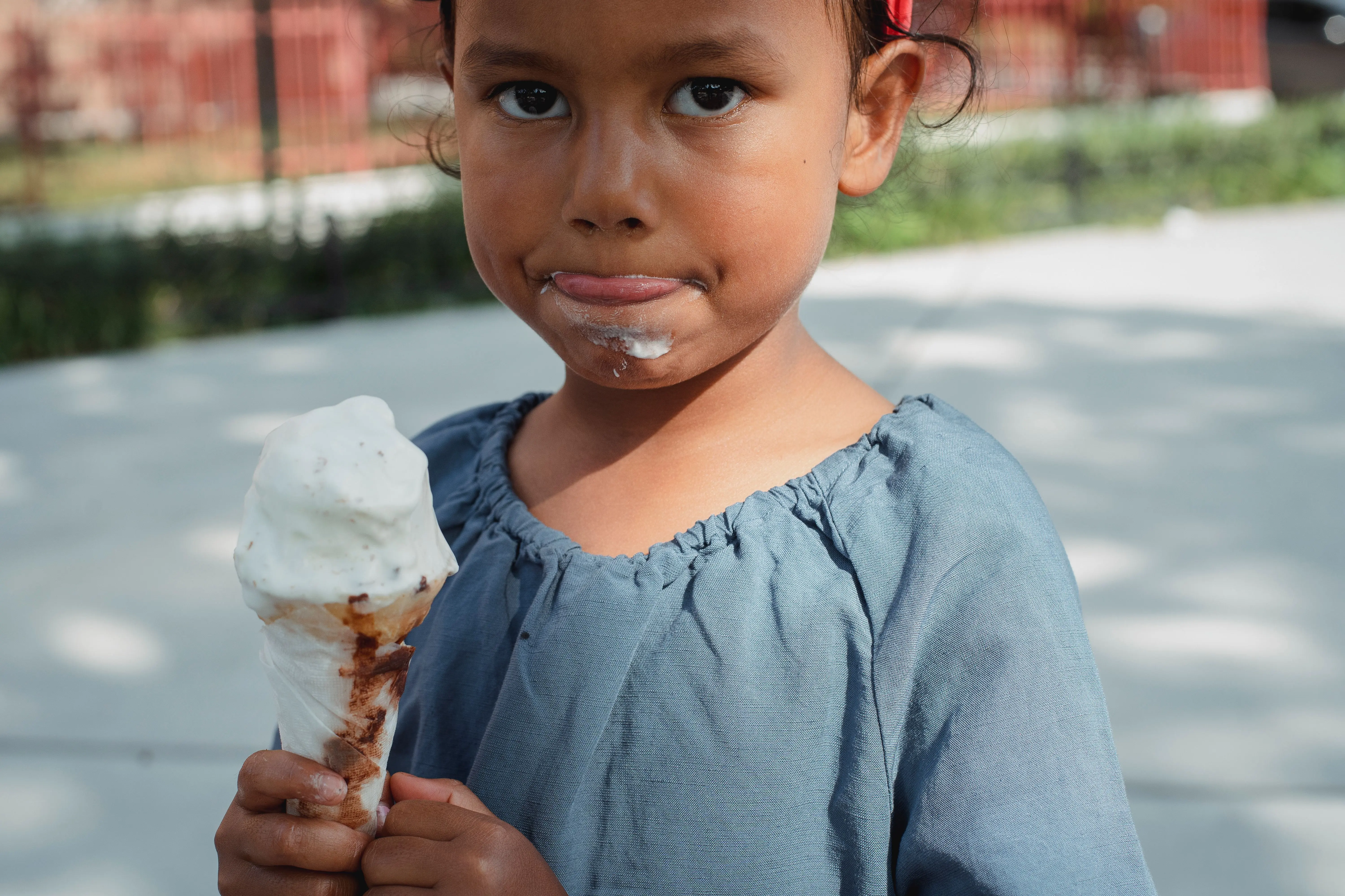 how to get grass stains out Crop adorable little Asian girl in casual clothes eating ice cream and looking at camera