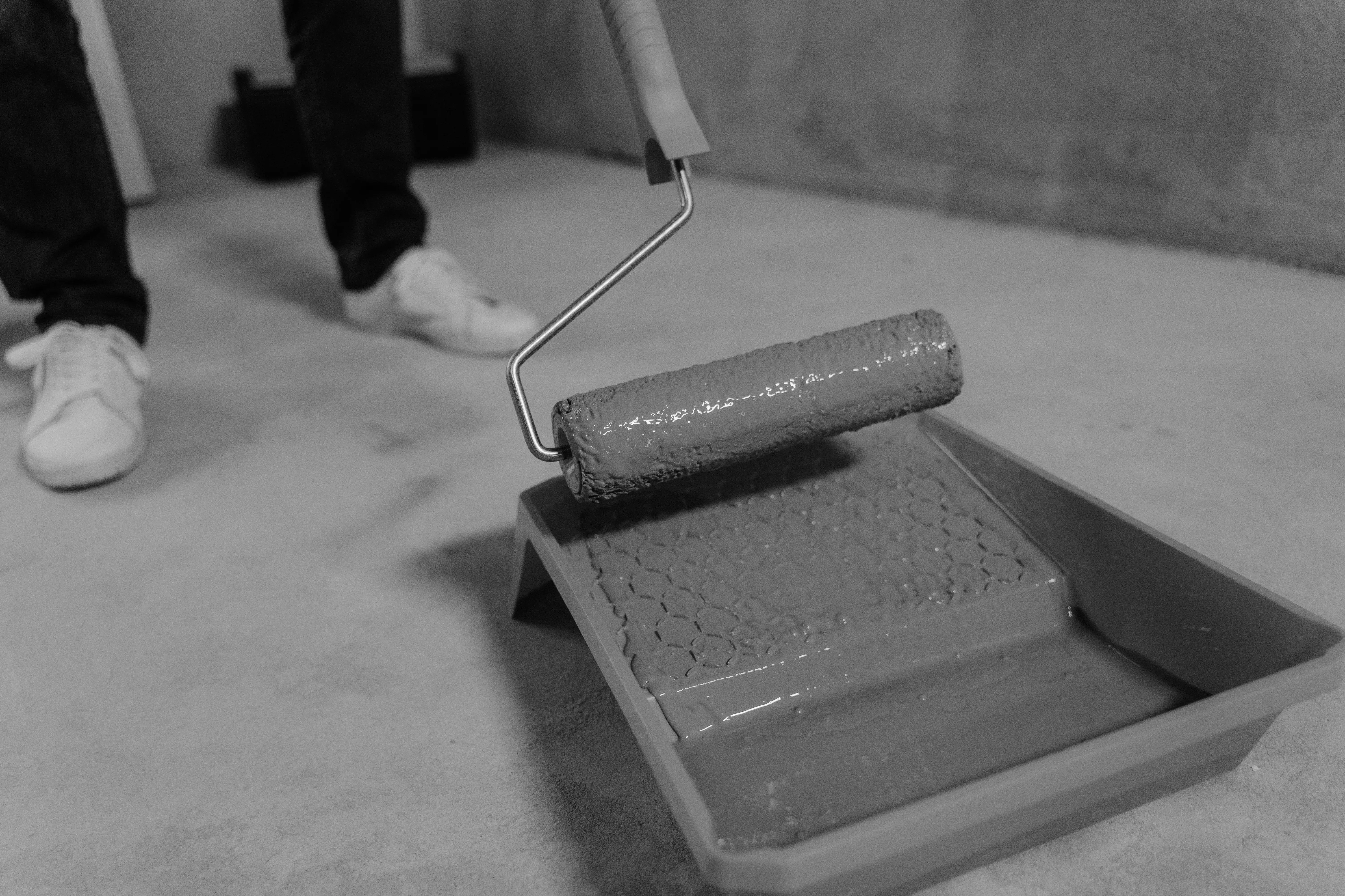 paint trays Black and white close-up of a paint roller and tray during a home renovation.