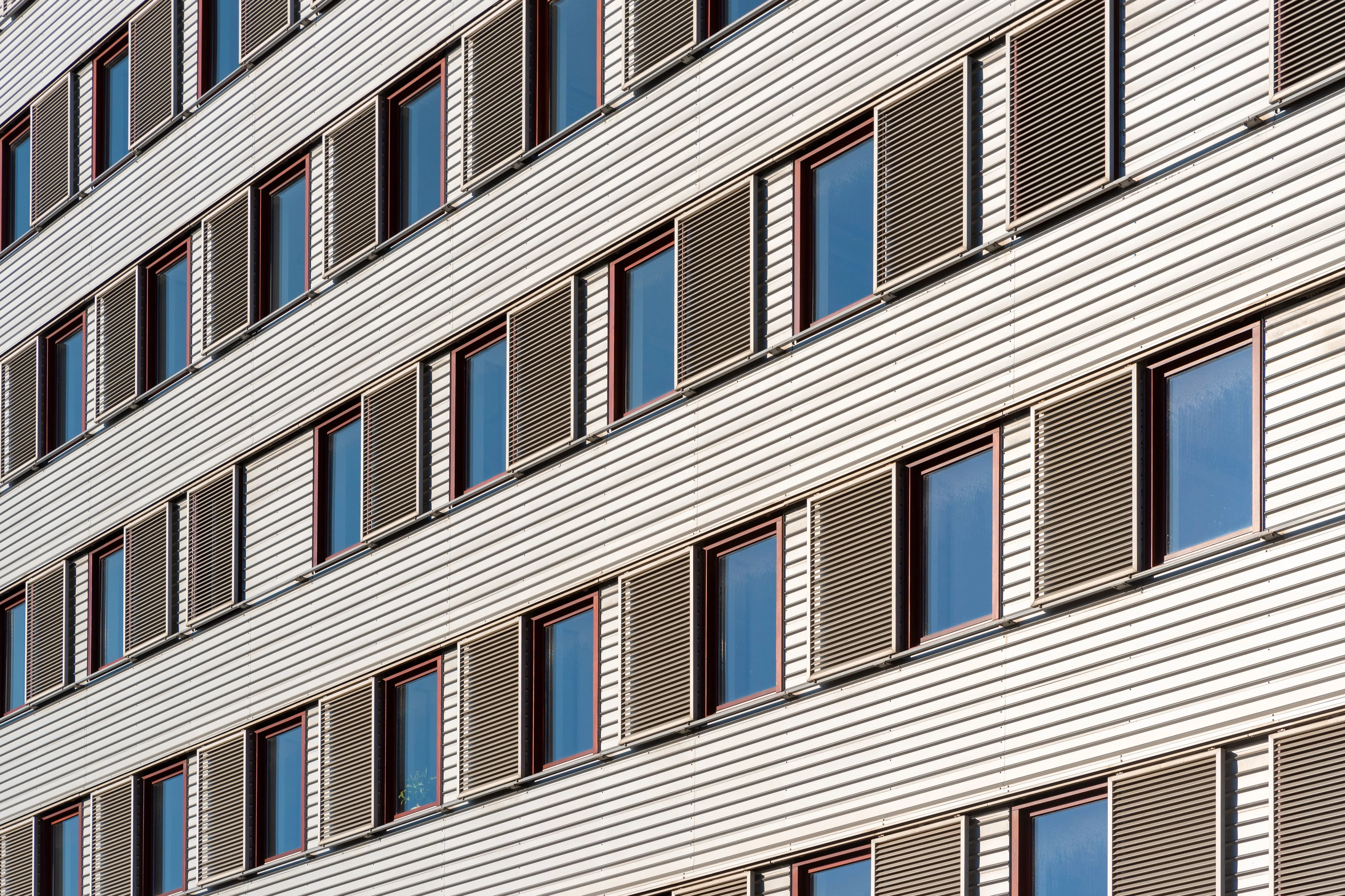 siding installation cost Geometric view of building facade featuring multiple windows and shutters.