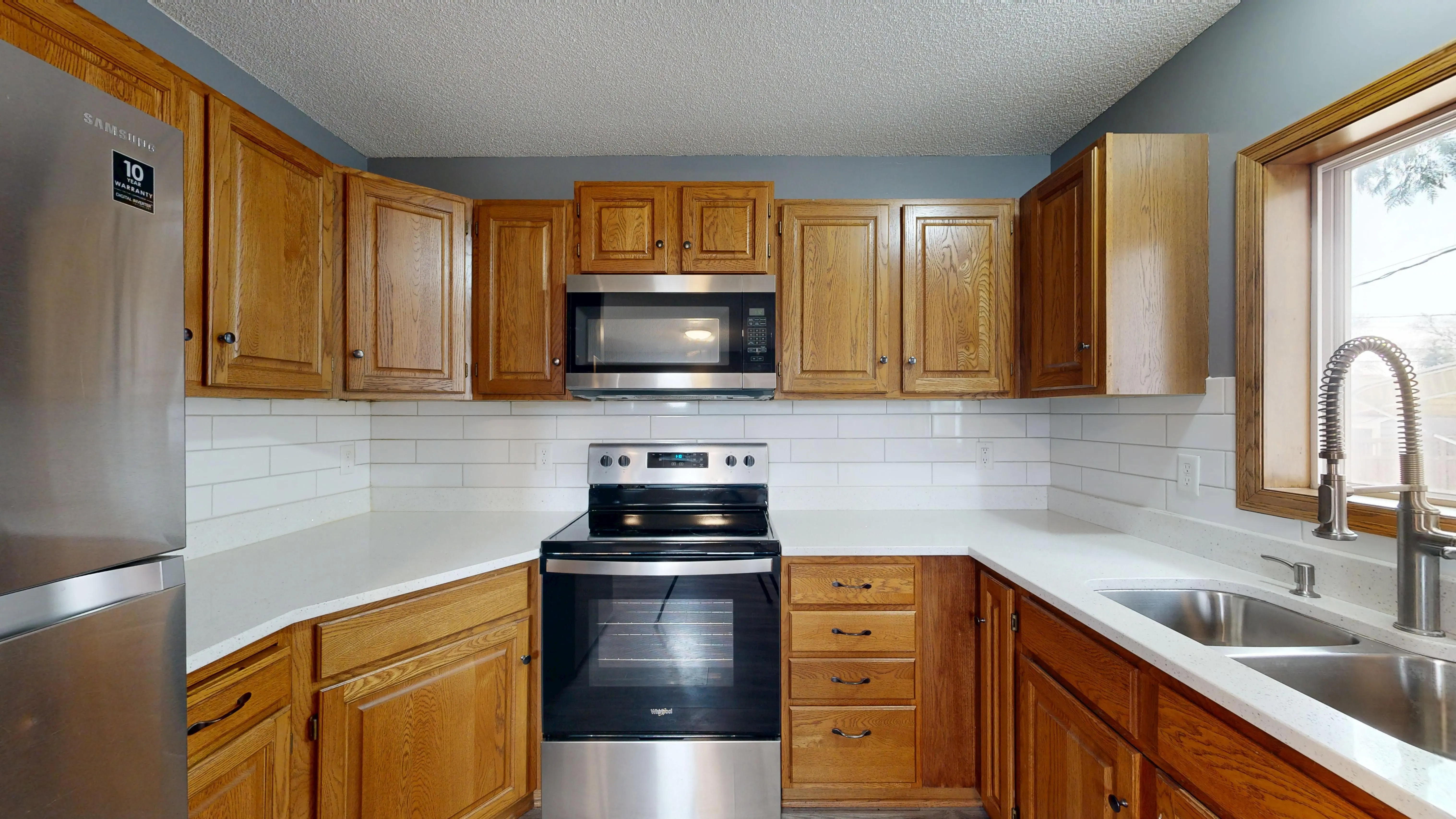 contemporary kitchen backsplash Stylish kitchen featuring wooden cabinets, modern appliances, and large window for natural light.