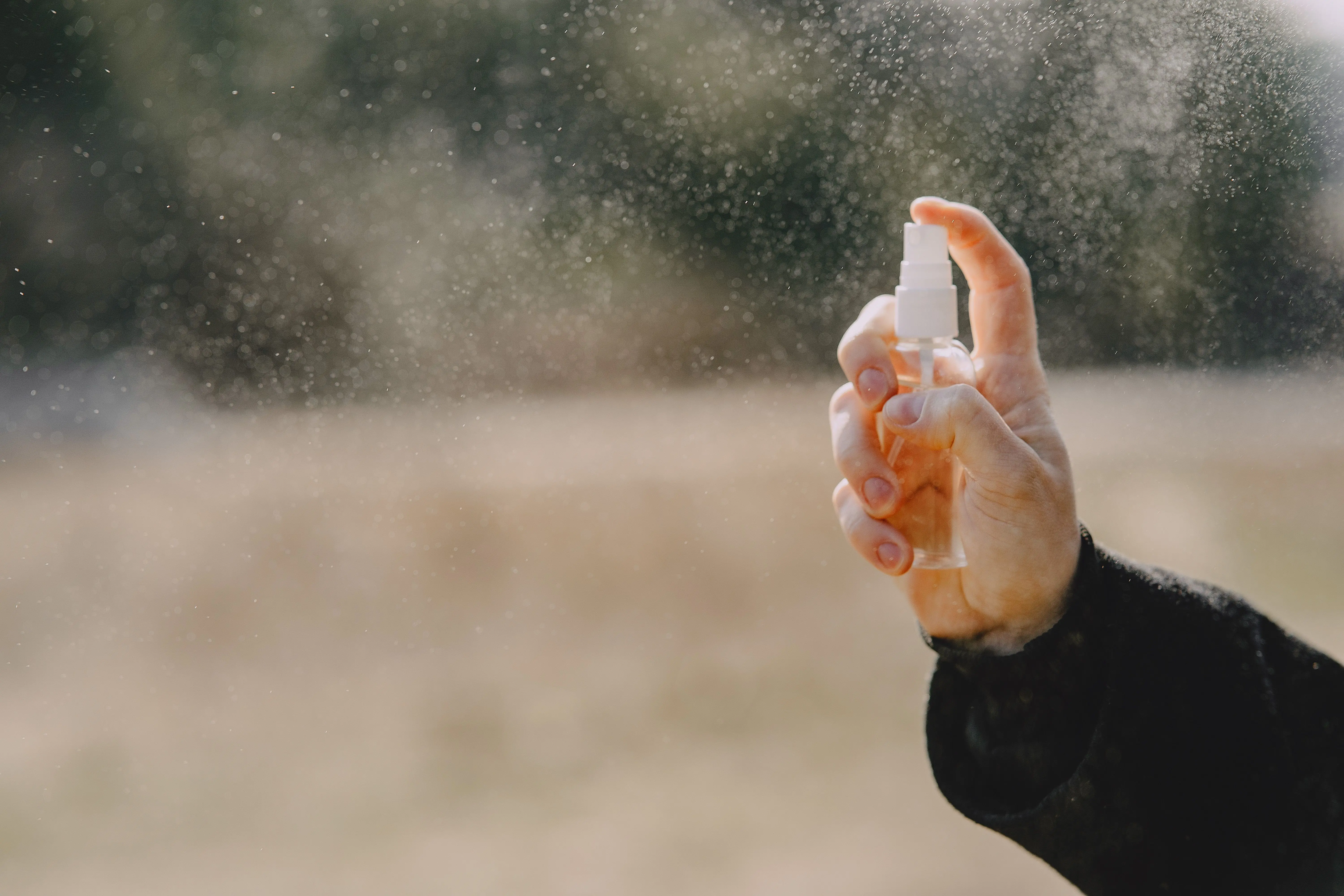 ant spray outdoor Unrecognizable man in casual wear showing bottle with liquid and spraying water outdoors