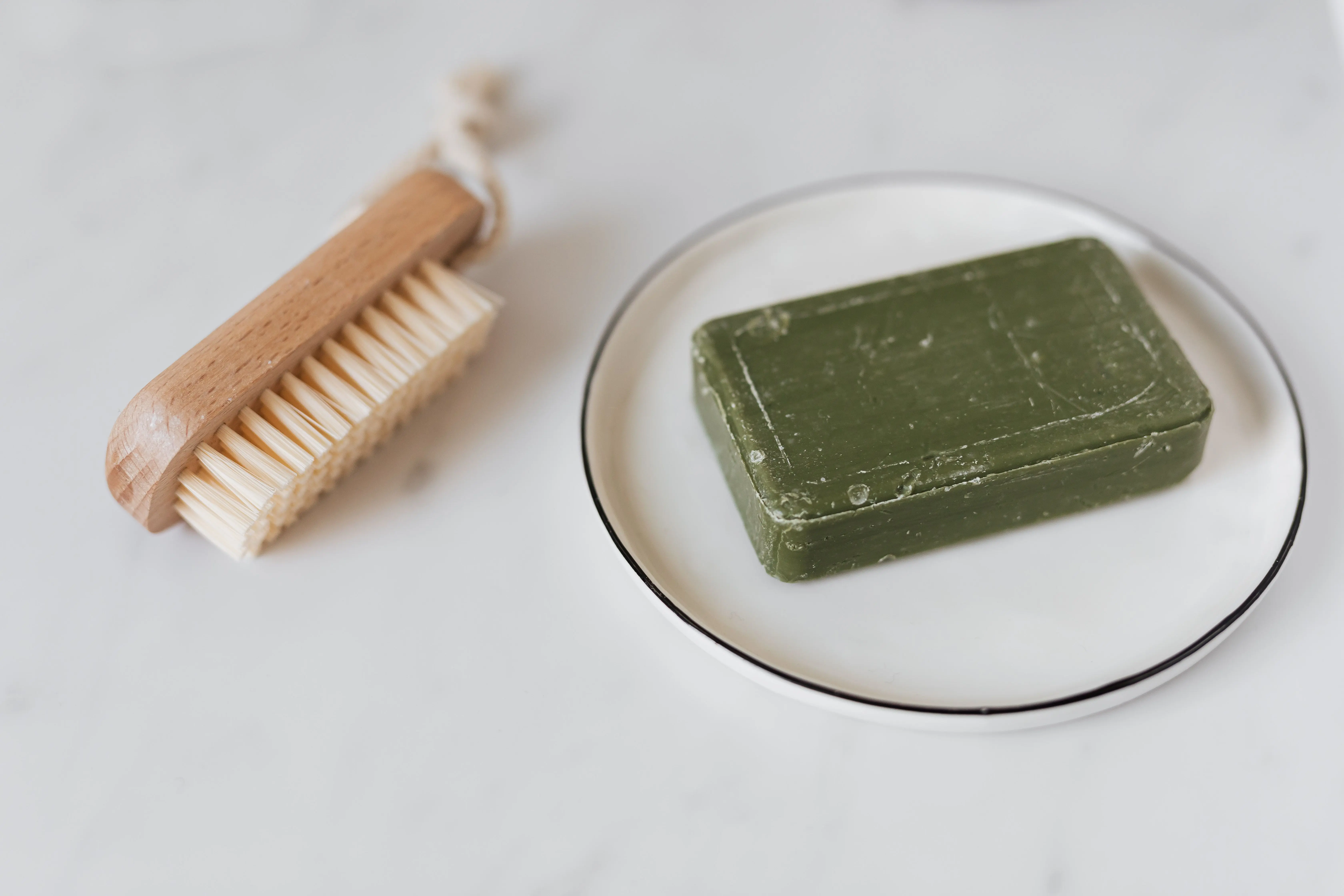 deep cleaning house checklist Minimalist photo of a green organic soap and wooden brush on marble for natural care.