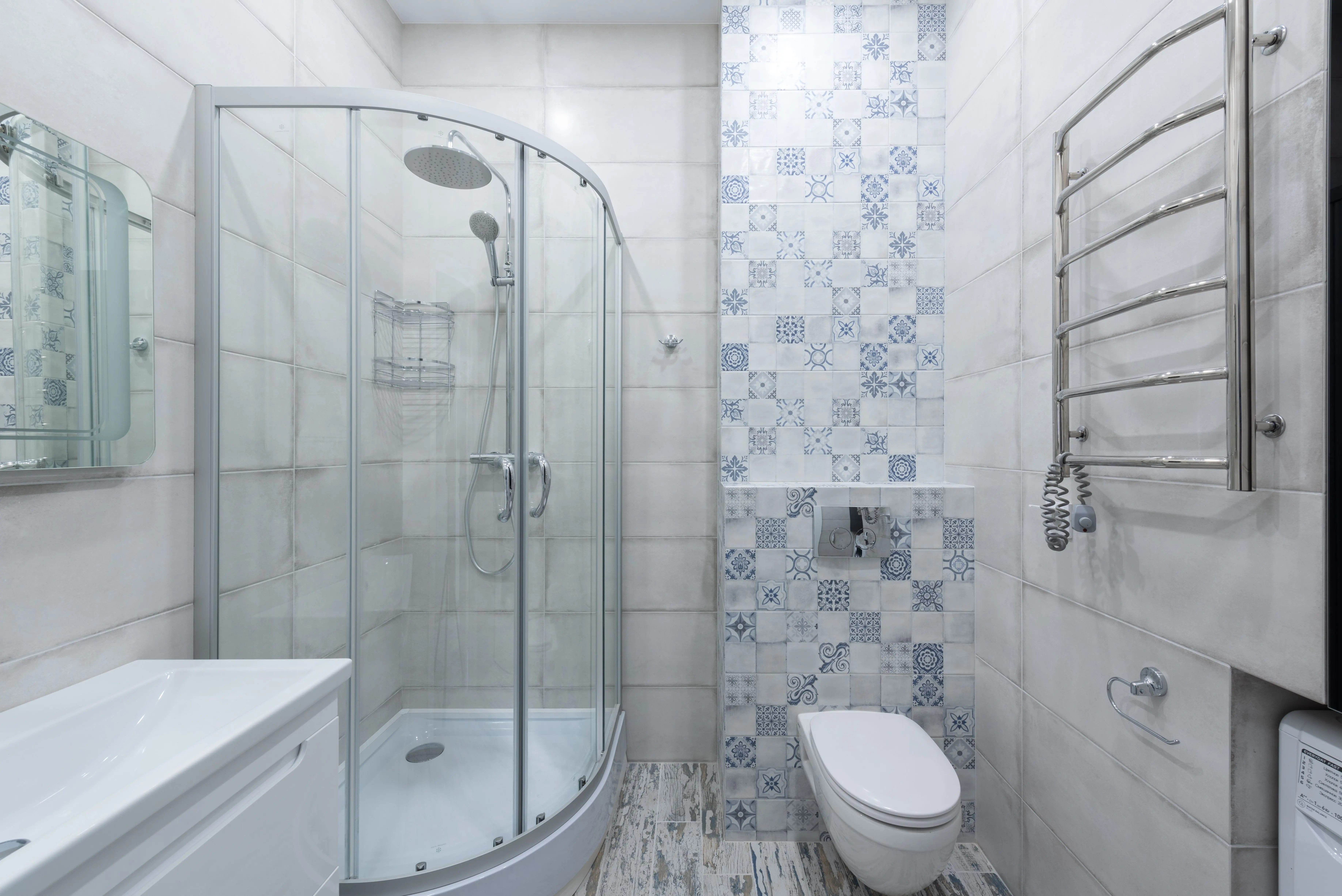 decorative tile Interior of light bathroom with glass shower cabin placed near toilet at wall with ornamental wall and white sink at home