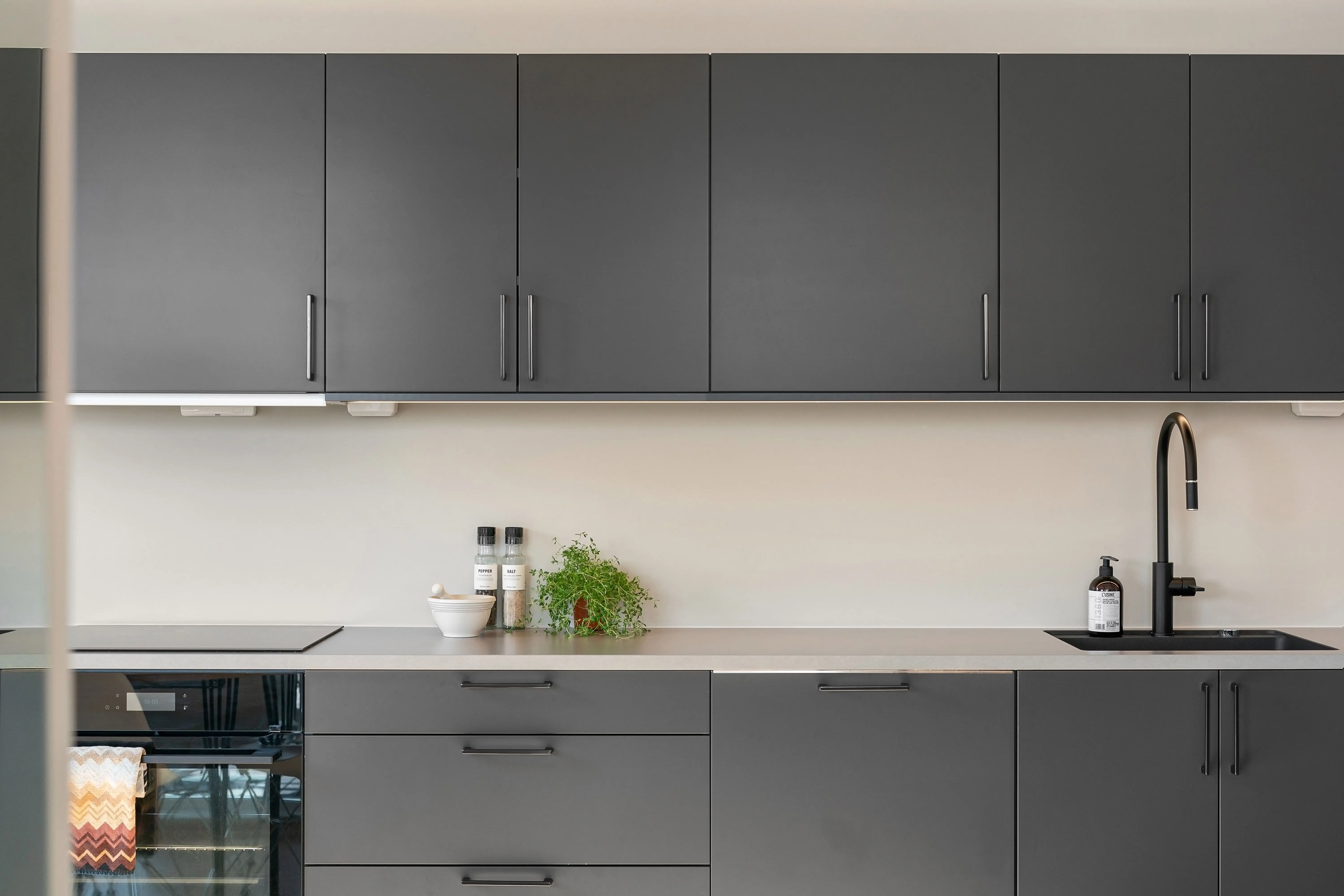 black cabinet handles A sleek, modern kitchen with dark cabinets, minimalist design, and stylish decor.